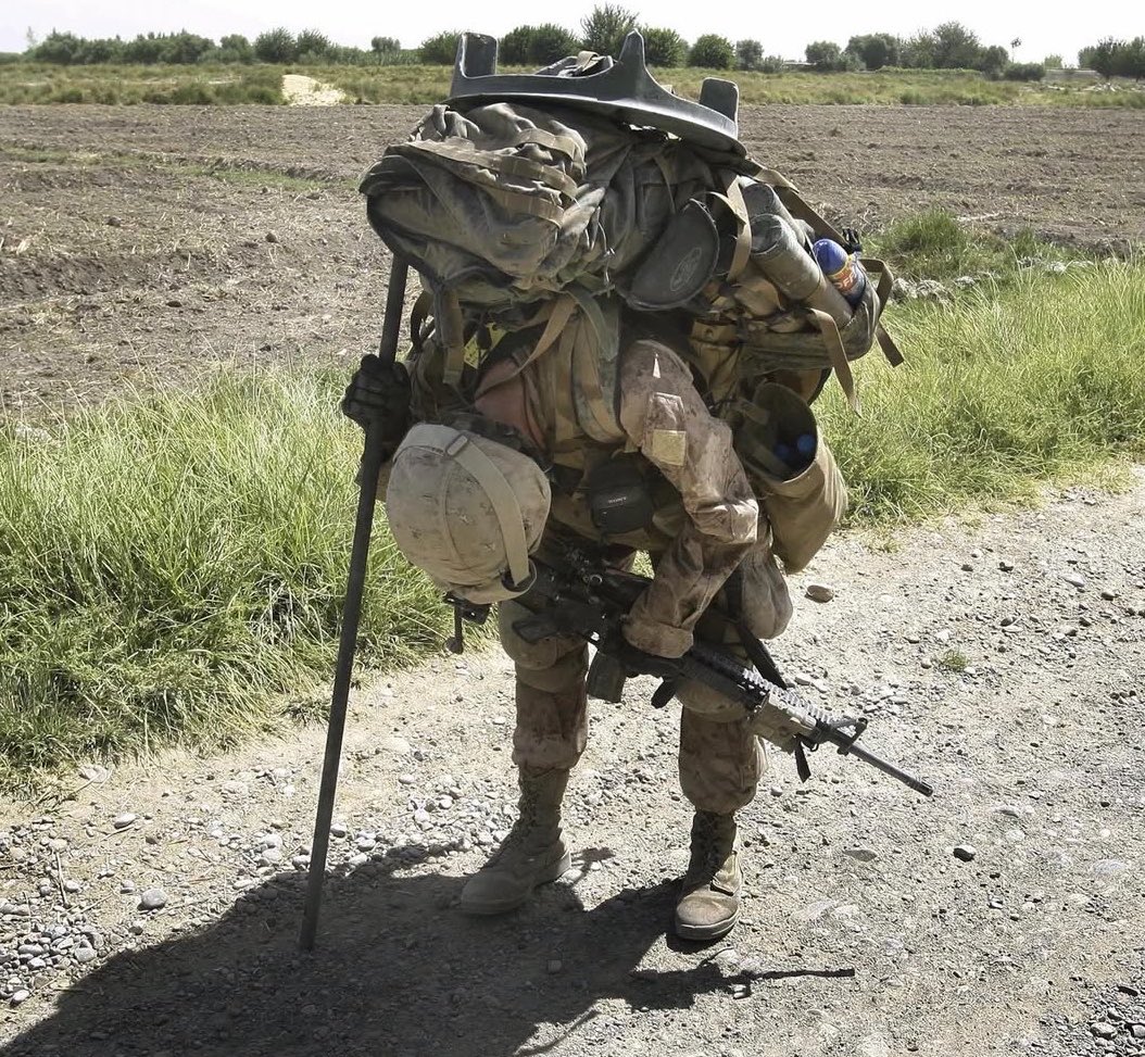 MilitaryCooI's tweet photo. 21 year old Marine Cpl. Brian Knight
pauses briefly in the heat to rest with his heavy pack filled with mortar baseplate, ammunition, food, and water. 

Afghanistan, 2009. https://t.co/yV6Mbf5uQ5