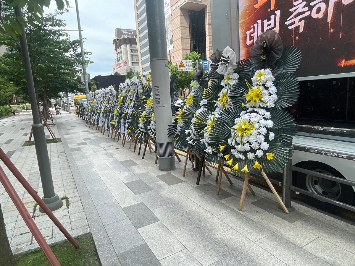 dopaminegyu's tweet photo. antis sent protest wreaths in front of the company bldg but thank god for the dino support truck parked beside it 😆 

dino i hope you don’t get discouraged and second guess your artistic decisions because of these wreaths, please go all-in with your plans because real carats are here to support you! 🦦
