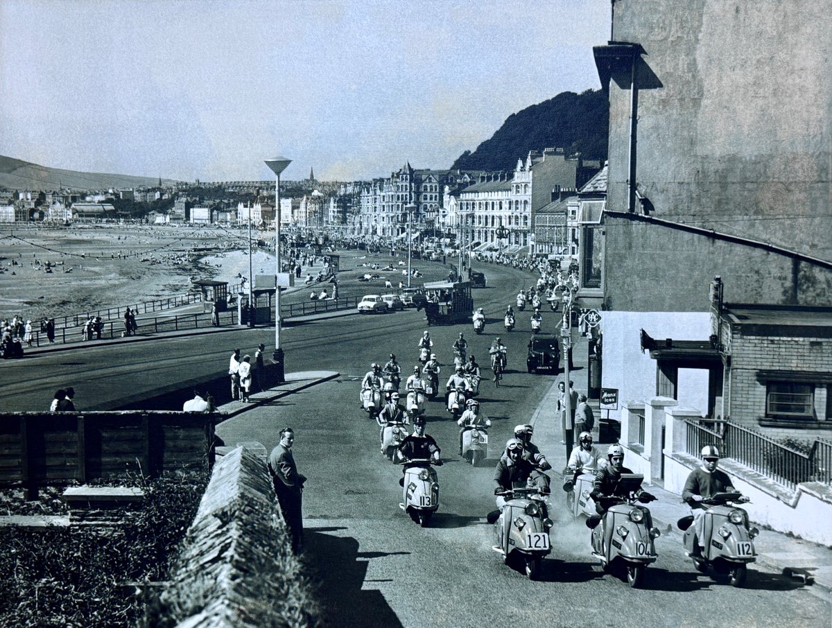ScooteringMag's tweet photo. Lovely print we have hanging in the office: Great scene from 1960 as riders mounted on DKR scooters head out of Douglas on then Isle of Man Rally.  #Scootering #Lambretta #Vespa #ClassicScooter #ScooterLife #ScooterScene #ScooterRally #ScooterClub #TwoStrokeLife https://t.co/wLuE5l15Iv