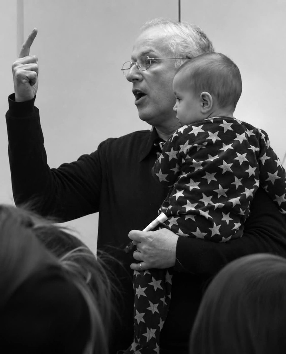 CrazyVibes_1's tweet photo. In May 2015, a baby started crying in a lecture hall at Hebrew University in Jerusalem.
What happened next would be viewed over a million times.
This is the story of Professor Sydney Engelberg—and the simple gesture that reminded the world what compassion looks like.

The classroom was filled with graduate students studying organizational management. Professor Engelberg, a 67-year-old social psychologist with five grandchildren and decades of teaching experience, was mid-lecture when the sound cut through the room.
A baby's cry.
In the back row sat a young mother. Her infant, dressed in blue footie pajamas covered in stars, had begun to wail.
She did what most student-mothers around the world would do. She stood up, embarrassed, ready to leave so she wouldn't disrupt the class.
But before she could reach the door, Engelberg did something unexpected.
He stopped his lecture. He walked calmly to the back of the room. Without asking permission, without saying a word, he gently took the baby from her arms.
Then he returned to the front of the classroom and continued teaching.
The baby calmed almost immediately.
For the rest of the lecture, Engelberg held the infant against his chest, explaining organizational psychology concepts as if this were the most natural thing in the world.
To him, it was.

Someone in the classroom snapped a photo. His daughter, Sarit Fishbaine, who happened to be present, posted it to Facebook.
Within days, it had been shared thousands of times. An Imgur post crossed one million views. News outlets from CNN to the BBC picked up the story. Engelberg became an overnight sensation in Israel, Russia, France, Brazil, and beyond.
The grandfather of five was suddenly being called "Professor of the Year" and "the newest feminist hero."
His wife, Fredi, found it all rather amusing.
"He's gotten love letters," she told Yahoo Parenting. "He's pretty blasé about it, and we just find it all very funny. I think it must have happened on a no-news day."
But millions of parents around the world disagreed. This wasn't a slow news day story. This was something they rarely saw: a figure of authority choosing accommodation over inconvenience, compassion over rules.

What the viral moment revealed was that this wasn't an isolated gesture.
For years, Engelberg had encouraged his students to bring their children to class. Mothers nursed their babies during his lectures. Toddlers occasionally wandered the aisles. He never asked anyone to leave.
When asked about his approach, Engelberg's explanation was characteristically humble.
"My motivation was very simple," he told TODAY Parents. "On a basic level, I love babies and wanted to help out."
But then he added something deeper.
"On a more sophisticated level, one cannot teach leadership and organizational behavior merely as content—you have to teach the value base as well and that means not just talking about values, but acting on them."
For Engelberg, welcoming mothers and their children wasn't charity. It was pedagogy.
"The reason is that education for me is not simply conveying content, but teaching values," he explained.

What many international viewers didn't realize was that Engelberg's gesture, while touching, wasn't unusual in Israel.
After the photo went viral, the Israeli Student Union's Facebook page was flooded with similar stories. Students posted photos of other professors holding babies mid-lecture. One student shared a picture of Dr. Orit Gilor from Beit Berl College burping her daughter after she'd finished breastfeeding in class.
"Israel is a very familial society," explained Jonathan Kaplan, vice provost of the Rothberg International School at Hebrew University. "It is not at all strange for young mothers to bring children to classes. Babies are often brought to weddings or formal occasions, and during school holidays it is not uncommon to see children running through the halls of office buildings or university departments."
There's also a practical reason Israeli students are more likely to be parents: mandatory military service. While American teenagers head to college at eighteen, Israelis first serve three years in the army. By the time they reach graduate school, many have started families.
The challenge of finding childcare is compounded by Israel's calendar, packed with Jewish holidays that don't always align with university schedules or daycare closures.
In this context, professors who welcome children aren't heroes. They're realists.

But if the gesture was ordinary in Israel, why did it resonate so powerfully everywhere else?
Engelberg had a theory.
"I think the photo went viral in a world with so much inhumanity—ISIS, corruption, Ferguson, and so on—and people are looking for symbols of decency, humanity, caring, integrity."
The image offered something rare: visual proof that kindness still existed in positions of power. That rules could bend. That a crying baby didn't have to mean exclusion.
For mothers around the world—many of whom had been asked to leave restaurants, courtrooms, airplanes, and classrooms for nursing or for having fussy children—the photo was validation.
Someone, somewhere, had chosen differently.

Professor Engelberg's credentials extend far beyond one viral moment.
He has taught at Hebrew University for decades across three faculties. He's an associate professor at Gratz College in Philadelphia and a visiting professor at the University of Bologna and the University of Florence. His consulting clients have included the World Bank, UNICEF, IBM, Microsoft, and Intel.
He has published widely, run executive training workshops on five continents, and founded the Program in Community Psychology at the University of New South Wales in Australia.
None of that made him famous.
A baby in blue pajamas did.

The photo from that day in Jerusalem captured something words often fail to express.
It showed that the smallest gestures sometimes carry the largest meanings. That a classroom can be more than a place for information transfer. That leadership isn't just taught—it's demonstrated.
Engelberg didn't give a speech about supporting working mothers. He didn't write a policy memo. He simply walked to the back of the room, picked up a crying baby, and kept teaching.
"I don't have any childcare secrets," he said afterward. "I think it is simply a matter of experience and transmitting a sense of security and calm, which babies naturally respond to."
Perhaps that's the real lesson.
Not just for babies.
For all of us.