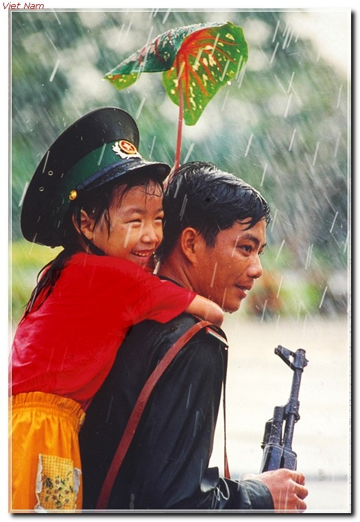 LonelyPAVN's tweet photo. A Vietnam Border Guard piggy-backing a child in downpour, 2000s https://t.co/Zu143pNomY