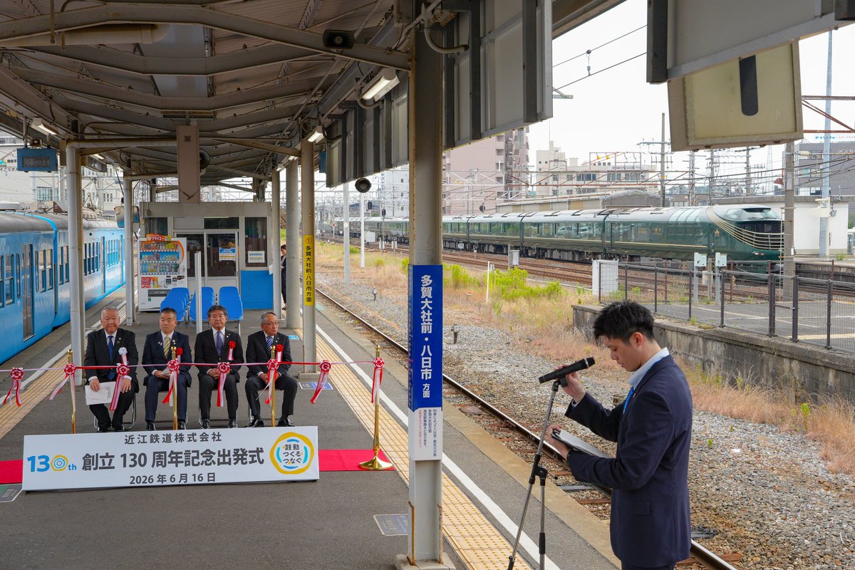 OHMI_railway's tweet photo. みなさんおつコンです🦊
先ほど創立130周年記念出発式の投稿をしたのですが、
実はこの式典中にお隣のJR彦根駅を「TWILIGHT EXPRESS 瑞風」が通過するという光景が‼️
JRさんからのお祝いかな？って思っています😄

担当:MF広報

#近江鉄道
#ガチャコン 
#式典後方から颯爽と瑞風
#シャッター間に合わず涙