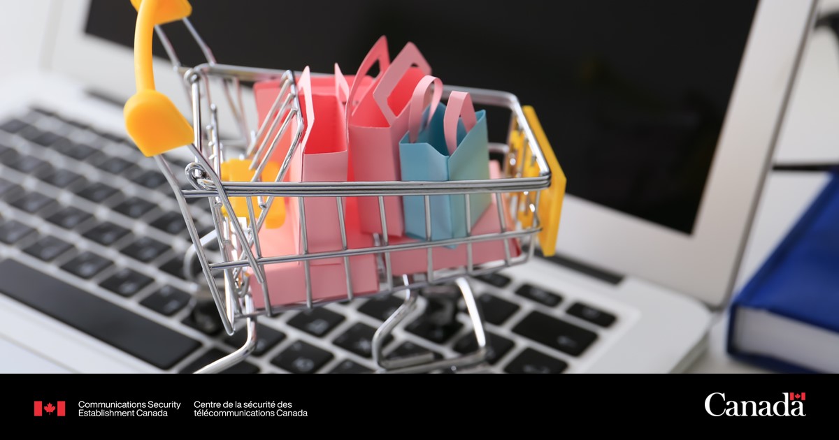 Miniature shopping cart filled with colorful paper bags placed on a laptop keyboard