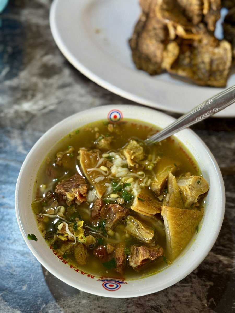 masakpartikelir's tweet photo. Soto Daging Sapi Pak Syamsul “LEJAR”, Pasar Colombo

Salah satu soto “unik” yang mewarnai persotoan duniawi di Jogja. Kuahnya tidak bening, mirip gagrak Lamongan tapi tanpa koya. Kaldunya dibuat dari bagian sandung lamur dan sengkel sapi. Kejutannya ada pada taburan bawang putih goreng. 

Isiannya sederhana saja. ￼ Nasi, tauge, daun seledri, dan daging. Standar. Yang tidak standar ada di lauk tambahannya.

Ada otak sapi goreng yang dibalur telur. Babat iso. Perkedel. Tempe garit kriuk. Semuanya lezat dan kenyal. Kondimen ada sambal yg agak encer, kicap manis, irisan jeruk nipis, dan lada.

Tempatnya cukup nyempil di sisi luar Pasar Colombo. Di antara toko buah dan toko makanan ringan. ￼ Tidak ada papan nama besar, tidak ada dekorasi. Kalau tidak tahu persis lokasinya, mudah kelewatan. Suasananya pasar betul, pembeli lalu-lalang, samar-samar terdengar suara tawar-menawar. ￼ Makan di sini terasa seperti ketidaksengajaan yang menyenangkan.

Arti kata LEJAR menurut abang yg jual adalah berkeringat kenikmatan saat menyanyap hidangan. 

Harganya liat sendiri ya, mau rate MBG atau mewah, monggo.

Sudah nyoto belum?