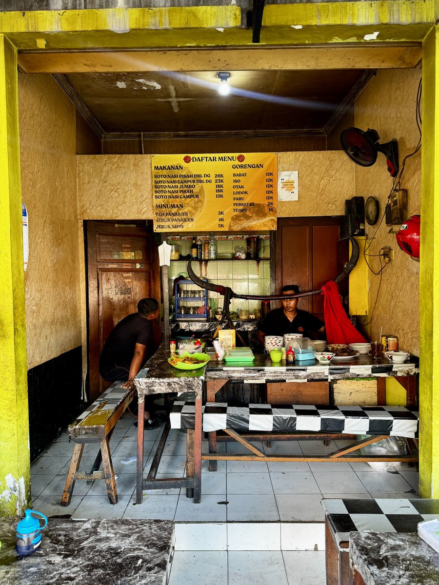 masakpartikelir's tweet photo. Soto Daging Sapi Pak Syamsul “LEJAR”, Pasar Colombo

Salah satu soto “unik” yang mewarnai persotoan duniawi di Jogja. Kuahnya tidak bening, mirip gagrak Lamongan tapi tanpa koya. Kaldunya dibuat dari bagian sandung lamur dan sengkel sapi. Kejutannya ada pada taburan bawang putih goreng. 

Isiannya sederhana saja. ￼ Nasi, tauge, daun seledri, dan daging. Standar. Yang tidak standar ada di lauk tambahannya.

Ada otak sapi goreng yang dibalur telur. Babat iso. Perkedel. Tempe garit kriuk. Semuanya lezat dan kenyal. Kondimen ada sambal yg agak encer, kicap manis, irisan jeruk nipis, dan lada.

Tempatnya cukup nyempil di sisi luar Pasar Colombo. Di antara toko buah dan toko makanan ringan. ￼ Tidak ada papan nama besar, tidak ada dekorasi. Kalau tidak tahu persis lokasinya, mudah kelewatan. Suasananya pasar betul, pembeli lalu-lalang, samar-samar terdengar suara tawar-menawar. ￼ Makan di sini terasa seperti ketidaksengajaan yang menyenangkan.

Arti kata LEJAR menurut abang yg jual adalah berkeringat kenikmatan saat menyanyap hidangan. 

Harganya liat sendiri ya, mau rate MBG atau mewah, monggo.

Sudah nyoto belum?