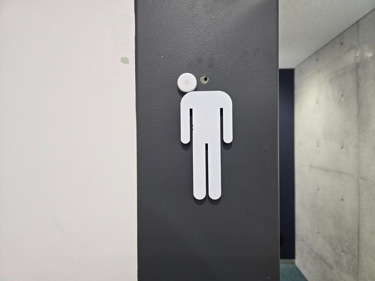 love_channnn's tweet photo. 【限界突破】
日本の大学にある「トイレのマーク」が、世界中で同情を買っている。
ただの故障が、あまりにも「現実」を映し出していた。

■舞台
東京理科大学。
「進級が日本一厳しい」とも囁かれる理系の名門校。

■事件の背景
トイレの案内表示の「頭」の部分が剥離。
偶然にも、肩のラインにピタリと着地した。
その姿は、重い足取りで絶望し、首を垂れる男そのもの。

■数字で見る過酷さ
・ストレート卒業率：約7〜8割。
・約2割の学生が留年や退学を経験する。
このマークは、そんな学生たちの「化身」に見えると話題に。

■世界への拡散
海外掲示板Redditでも「過労死（Karoshi）のサイン」と拡散。
「日本人はトイレの表示まで残業させているのか」
「背景を知ると笑えない」と驚愕の声が集まった。

ただのシール剥がれが、どんな警告文よりも心に刺さる。
たまにはマークも、学生も、ゆっくり休んでほしい。

明日の自分を見ているようで、他人事とは思えない。