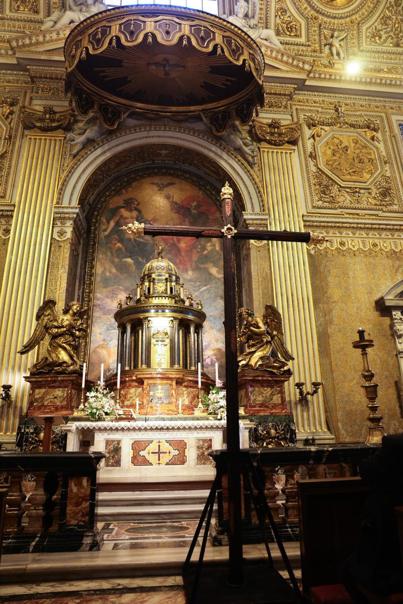 RociodeMalaga's tweet photo. ⚜️𝐂𝐎𝐑𝐏𝐔𝐒 𝐂𝐇𝐑𝐈𝐒𝐓𝐈 • Nuestra 𝐂𝐫𝐮𝐳 𝐝𝐞𝐥 𝐌𝐮𝐧𝐝𝐨 presidirá el altar del Corpus en la Plaza de la Constitución.

Preparado por Albacería de Cultos, este altar nace como expresión de nuestra identidad y de nuestro carácter sacramental. En él se reflejan la alegría, la fe y la devoción a la Santa Cruz de Nuestro Señor, verdadero símbolo de Redención.

La gran protagonista de este altar es la Cruz del Mundo, estrenada con motivo del cincuentenario de Nuestro Padre Jesús de los Pasos en el Monte Calvario. En sus llagas se representan las distintas escenas del Vía Crucis, evocando así el motivo fundacional de nuestra corporación nazarena y recordando el camino de la Pasión. 

La Cruz del Mundo se presenta escoltada por un resplandor, la luz de la cera y una cuidada exornación floral, elementos que realzan su significado espiritual y devocional. 

Se alza sobre el antiguo trono del Santísimo Cristo del Amor, pieza que hoy pertenece a la Hermandad de Medinaceli. Este detalle aporta un sentido alegórico al conjunto, pues Cristo se entregó al mundo por amor, convirtiendo el sacrificio en la cruz como la máxima expresión de la caridad divina.

El conjunto se encuentra arropado por el dosel estrenado para la Magna Mariana dedicada a Santa María de la Victoria, en la que participó la Virgen del Rocío Coronada. Su presencia aporta al altar un marcado carácter victoriano y evoca los históricos vínculos de nuestra Hermandad con la Victoria y su excelsa Patrona.

A ambos lados de la composición se sitúan San Francisco de Paula, fundador de la Orden de los Mínimos, ligado al origen de la Hermandad y al barrio de la Victoria, además de patrono de Málaga; y Santa Elena, emperatriz romana y figura clave por el hallazgo de la Santa Cruz. Ambos refuerzan el protagonismo de la Cruz como eje central del altar y su significado en la tradición cristiana.

Completa el altar un rico conjunto compuesto por consolas, hachones, candelabros y una exornación floral en tonos blancos, elegidos para aportar pureza, dignidad y distinción al conjunto, realzando así el carácter solemne y sacramental de este altar del Corpus.

#CofradíasMlg