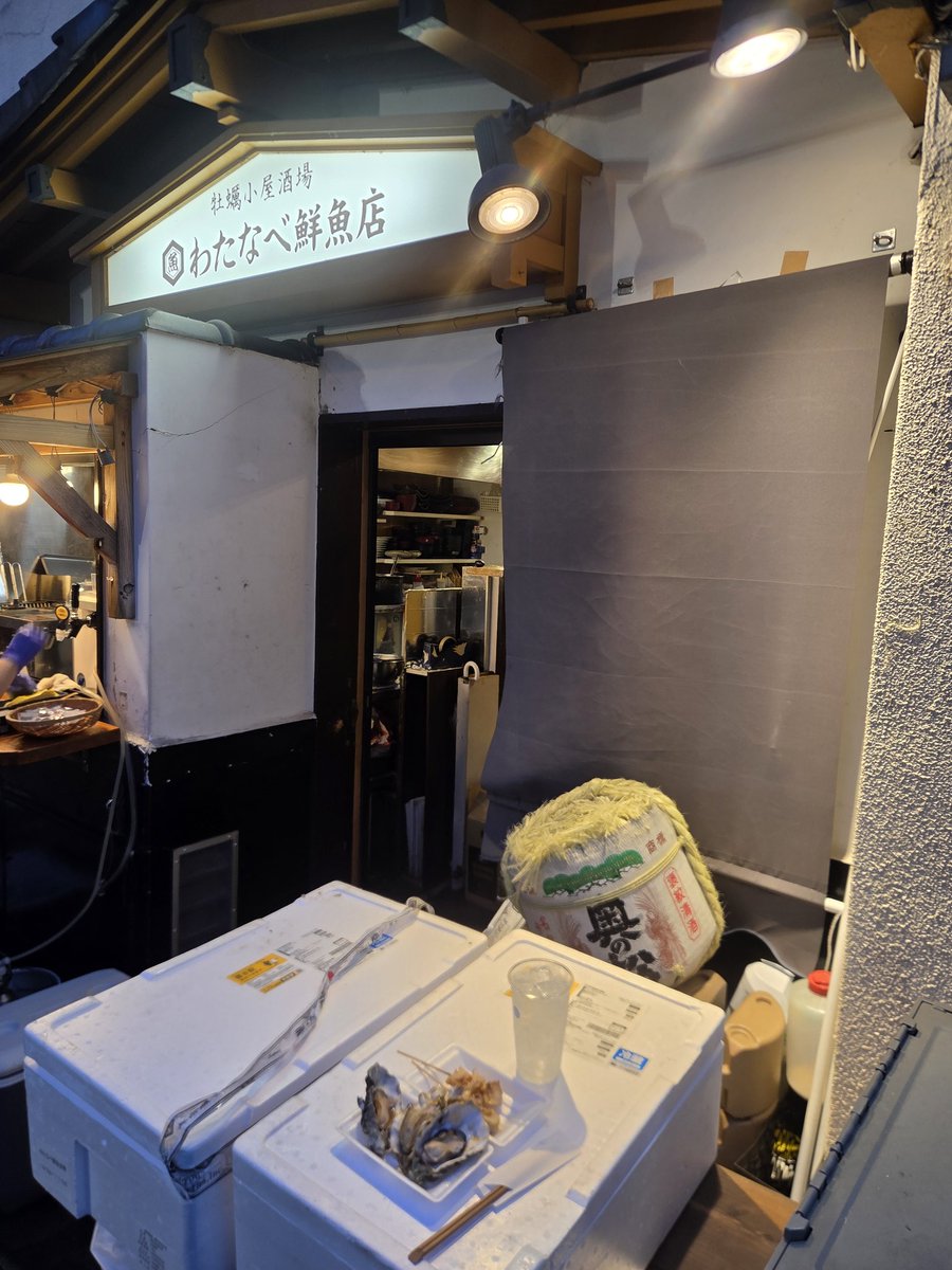 ganocchi's tweet photo. 通りの一角に店頭にやたら並びのある店を見つけ、何か気になる。
ただそれは祭りの見物人のためテイクアウト用の酒やツマミを買い求める客のようで、入店を待つ並びではない模様。
店内を覗くとカウンターのみ数席しかないようではあるが見たところ満席。
一応入れるのか聞くと、小一時間待てば入れるとのことなので直感に従い待つことに。
ただ待ってるのも何なので他のテイクアウト客の並びに着き、入店前に店頭で俺も始める。
つかつぶ貝のバター醤油焼きも牡蠣のカンカン焼きだとかもうめえ！これは期待できるぞ。