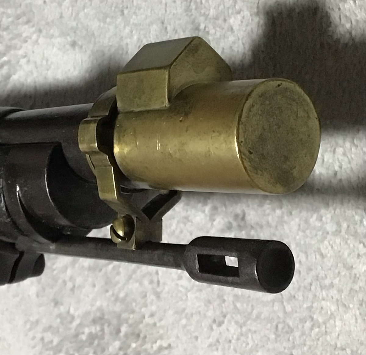 L4xdbBmFLm96386's tweet photo. 十八年式村田銃の銃口蓋。
取説にも記載が無い。
真鍮製の非常に凝った造り。
ただ嵌めるだけでない。
銃剣の回り止めのキーを使って、嵌合する。
それを避ける膨らみは丁寧に鑞付けされている。
銃口に被せたあと、さらに回転部を180度回す。
すると、さく杖にパチンと嵌まる。
さく杖をバネとして使う合理性。
このように凝った銃口蓋は、他に類を見ない。
GUN誌の日本の軍用銃のレポートで有名な吉田四郎氏。
氏に、こんな物がありますよと伝えた。
すると、写真をご所望。
氏は、ネットをされない。
隣の州にお住まいの妹さんに送る。
プリントアウトして持って行くという手間をかける。
すると、1週間後に、同じ銃口蓋が送られて来た😱
吉田氏の手作りだ。
なぜ、こんな早く？
「俺も、十八年式は持っているからね🤣」
いや、そう言う問題じゃ無い。
根っからの日本の軍用銃マニア。
そして昔気質の職人だった…。