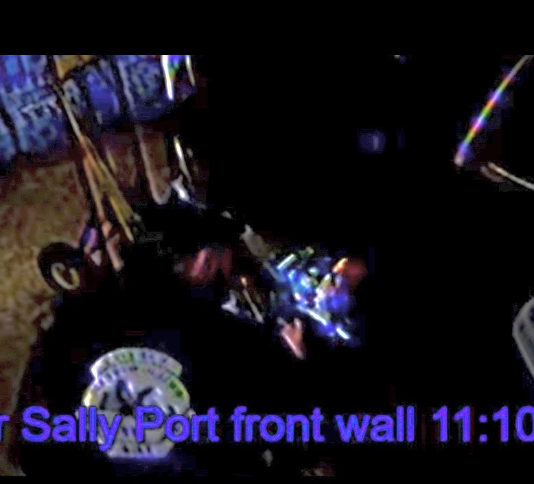 SharSays's tweet photo. Yet another non-uniformed person (actually two) in the Sallyport at the back of the Lexus TOUCHING it. The crime scene tape? Moved to be under the bumper to allow access. No, the lights were not on. I’ve brightened it. One appears to have facial bruising &amp; be on the phone. https://t.co/ngUGn9QKNd