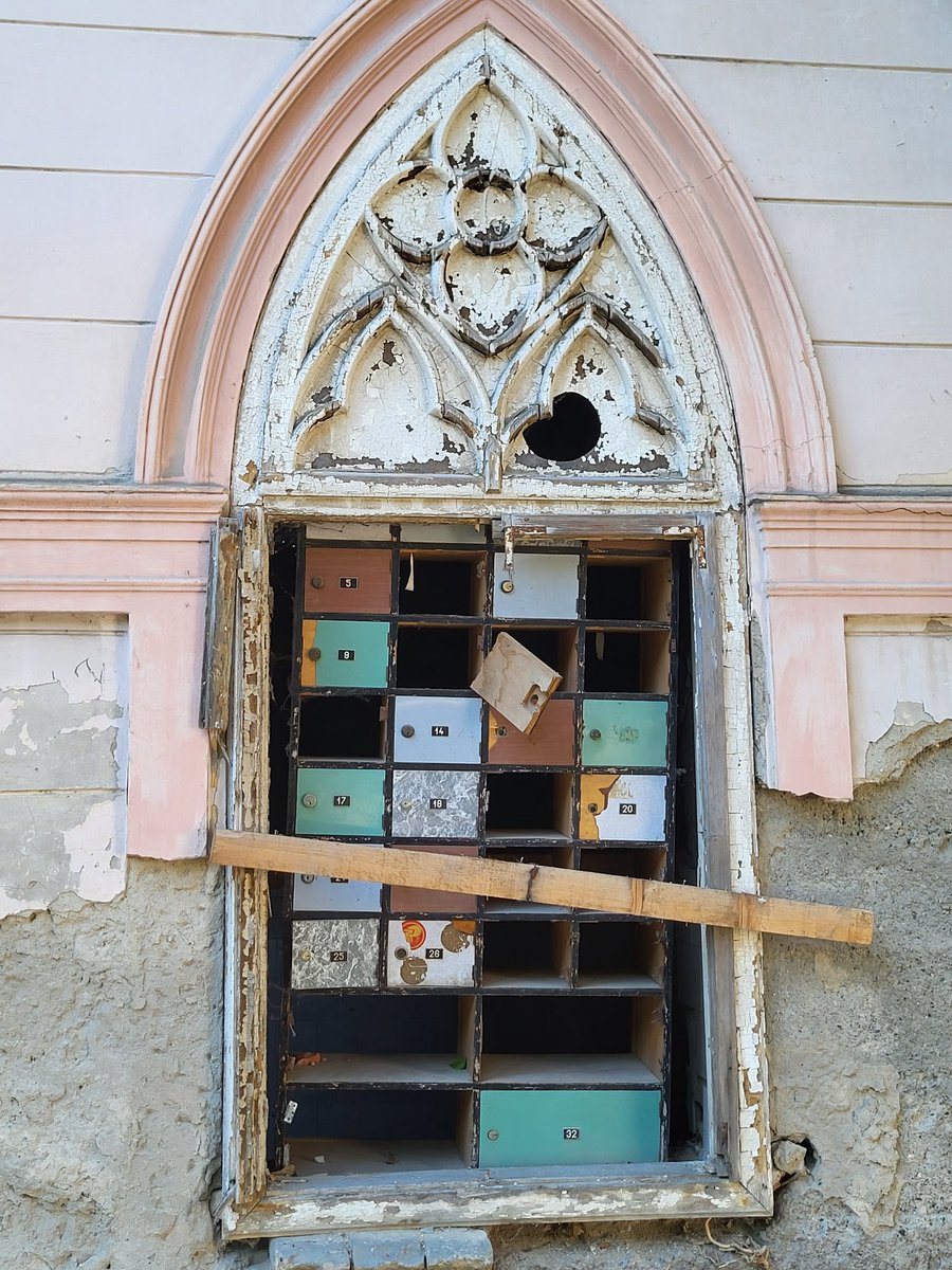 robert_coban's tweet photo. Pre dve godine Beočin je posetila Katarina Mendiondo iz Brazila, unuka Flore Špicer i praunuka Edvarda i Ane Špicer, nekadašnjih suvlasnika Beočinske cementare o čemu sam tada pisao za "Vreme" u tekstu "Devojke iz Brazila". Zatekla je ostatke sjaja vile i dvorca koje su posedovali njeni preci. Pre nekoliko godina ušao sam u zgradu Stare pošte u Beočinu, u nekadašnju rezidencija Špicerovih. U njoj je na podovima ostao razbacan inventar Pošte zaostao nakon njenog preseljenja. Na zidu je još uvek bio cenovnik poštanskih usluga, kao i boks sa pretincima u kojima je ostalo i po neko, nikad dostavljeno pismo. Zapamtio sam tada nadrealnu scenu: drvo koje raste na masivnom kamenom balkonu iznad glavnog ulaza u vilu.
U aprilu 2024. prijatelj iz Beočina poslao mi je fotografiju na kojoj se vidi da je priroda pobedila arhitekturu – korenje drveta se toliko raširilo da je odvalilo balkon koji se srušio na travnjak ispred.
Tu scenu će u svom oku u Brazil poneti i Katarina, praunuka Edvarda i Ane Špicer, koji su u nekim lepšim vremenima na tom balkonu gledali neki lepši Beočin.
Kada sam bio u Beočinu u novembru 2025. zatekao sam radnike koji su čistili šut iz vile i rekli su mi da je ista prodata i da će uskoro biti obnovljena. Međutim, sedam meseci kasnije vila je i dalje zapuštena. Na jedan prozor navaljena je nekadašnja polica sa poštanskim pretincima a kroz jedan od prozora se vidi da se masivna poštanska kasa i dalje nalazi u prostoru.
https://t.co/ShVO9II1e2