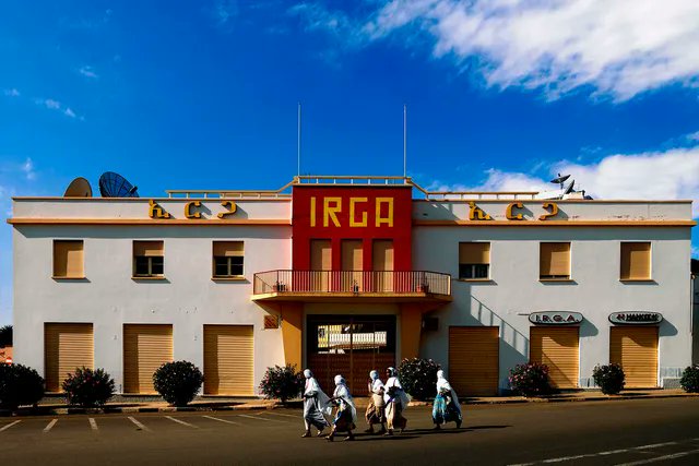 NestorSiurana's tweet photo. La capital de Eritrea fue diseñada por arquitectos italianos en los años 30.

Es la mayor concentración del mundo de arquitectura futurista y Art Déco, congelada en el tiempo.

Y sí, Asmara está reconocida oficialmente por la UNESCO como Patrimonio de la Humanidad.

Durante la ocupación colonial italiana, el dictador Benito Mussolini quiso transformar la pequeña ciudad en una metrópoli de vanguardia que sirviera como vitrina del fascismo en África.

Al estar lejos de las estrictas normativas urbanísticas de Europa, los arquitectos italianos utilizaron Asmara como un laboratorio experimental para plasmar las ideas más radicales de la época.

Especialmente entre 1935 y 1941, se levantaron miles de edificios con líneas aerodinámicas, ventanas de buey y formas geométricas audaces.

El Fiat Tagliero (1938), es la obra cumbre del futurismo arquitectónico.

Diseñada por Giuseppe Pettazzi, es una estación de servicio con la forma de un avión de pasajeros y espectaculares alas de hormigón voladizas que se sostienen sin pilares.

El Cinema Impero (1937), también es el máximo exponente del Art Déco en la ciudad.

Destaca por su imponente fachada vertical, sus motivos geométricos y los portones de cristal inspirados en circuitos eléctricos.

Bar Zilli y otros comercios también son edificios que simulan la forma de un aparato de radio antiguo, villas residenciales cubistas y hoteles con interiores idénticos a los de la década de 1930.

¿Pero por qué se congeló en el tiempo?

La ciudad sobrevivió intacta debido a décadas de aislamiento político y a un largo conflicto de independencia con Etiopía.

La falta de recursos económicos impidió el desarrollo inmobiliario moderno, protegiendo sin querer todo el casco histórico de la demolición y preservando el entorno urbano tal como lo dejaron los italianos en 1941.