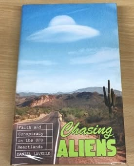 hauntedmagazine's tweet photo. **BOOK REVIEW**
Chasing Aliens: Faith & Conspiracy in the UFO Heartlands by @DaniLavelle 

There are many ways to look for aliens. You can scan the skies with expensive equipment, interview government whistleblowers, stare meaningfully at declassified Pentagon footage, or, as Daniel Lavelle brilliantly does in Chasing Aliens, head deep into America’s UFO heartlands & politely ask the strangest people in the room what on Earth, or indeed not on Earth, what the bloody hell is going on.

The result is part road trip, part investigation, part existential wobble, and part “did that man just say space beads?” travel diary. It is funny, thoughtful, odd, humane, and occasionally so American it practically comes with a side order of fries & a man in the desert insisting the truth is definitely out there, pointing you in a certain direction, to walk about 500 yards and then take a left after you’ve passed the gift shop.

Daniel never treats the UFO world as one big punchline. He is sardonic without being cruel, curious without being gullible, and sceptical without turning into the sort of bloke who folds his arms at a séance and ruins everyone’s evening [there are people out there like that].

Across sky watches, abductee stories, government whispers, alien believers, Starseeds, crystals, Harvard astrophysicists and the ever-hovering possibility that the Pentagon knows more than it is letting on, Chasing Aliens becomes less about whether aliens exist and more about why we so desperately want them to. 

Are we searching for evidence, salvation, meaning, community, or just someone else to blame for the state of the planet? Let’s be honest here, if aliens have been monitoring us recently, they’ve probably locked the doors, hidden behind their sofas and pretended not to be in.

There’s a small spattering of Louis Theroux here, with Daniel wandering into strange spaces and allowing people enough room to reveal themselves, their beliefs and, occasionally, their full interdimensional admin. But underneath the humour is something sadder & more human. This is a book about loneliness, faith, uncertainty and the deep, strange ache of being alive on a small rock, looking up at a massive sky, wondering whether anyone is waving back.

It is also extremely entertaining. There are moments when I felt like I was in a pub conversation with my mates when one of them asks, “Do you reckon aliens are real?” and then fast forward to 1.40 am and I have a kebab in my hand while my mate Andy is trying to explain that Oumuamua might be a probe, my mate Jason is telling me that the government is hiding spacecraft, and that my mate Simon declares that he once saw a cigar-shaped object in the sky.

It’s clever that Daniel doesn’t offer easy answers here; I often wonder if there will ever be any. Instead, he gives us people: believers, seekers, insiders, outsiders, dreamers, grifters, mystics and the beautifully bewildered. And I won’t sugarcoat this; whilst some are quietly convincing, some are slightly concerning. 

There are many fantastic UFO books out there. Chasing Aliens is a sharp, warm & wonderfully strange journey through the modern UFO landscape. It understands that the flying saucer has never just been about the flying saucer. It is about fear, hope, belief, distrust, wonder and the eternal human need to point at something weird in the sky and say, “What the frick is that?”

Funny, fascinating and quietly haunting, this is a book for anyone who has ever looked up and wondered whether we are alone, whether the government knows, and whether the aliens, if they are out there, have any plans to help us sort out the mess we are making of our planet. 

In short: a brilliant, bizarre and beautifully written trip into the UFO underworld. Come for the aliens. Stay for the humans, who are probably, actually, possibly stranger.

I had the great fortune to pick up Daniel’s book in a charity shop, but I would imagine it is available anywhere you can buy books. Please support the good and great indie bookshops out there if you can.

Please feel free to share this review #bookpublishing #bookreviews #booksworthreading #UFO #Aliens #bookrecommendation #booktwitter