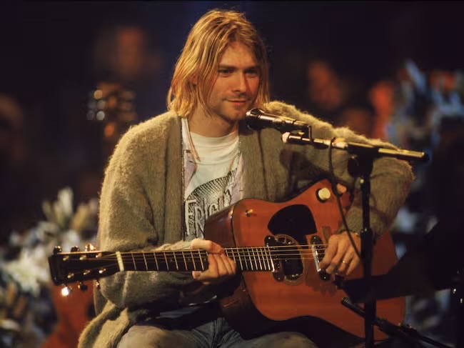 historyrock_'s tweet photo. “Come as You Are” is one of grunge’s most iconic anthems, written by Kurt Cobain and included on the album Nevermind (1991)

It was one of the new songs Nirvana recorded with producer Butch Vig at Sound City Studios (California) in 1991. Cobain created the iconic watery riff using a Small Clone chorus pedal; Krist Novoselic follows with the bass and Dave Grohl with the drums. The line “No, I don’t have a gun” accidentally made it into the vocals.

After the Nevermind boom, the label wanted to release it as the second single, though Cobain hesitated because the riff closely resembles that of Killing Joke’s “Eighties” (1985). The British band was upset and considered suing, but didn’t. Years later, Dave Grohl played drums on a Killing Joke album, sealing the peace.

The video, directed by Kevin Kerslake, was shot in a hangar with water pouring down, a baby swimming (a reference to the Nevermind cover), and a gun sinking. It reached the top 10 in several countries and remains a classic. In 2005, Aberdeen (Cobain’s hometown) put up a sign reading: “Welcome to Aberdeen – Come as you are.” It also features a memorable acoustic version on the 1993 MTV Unplugged.