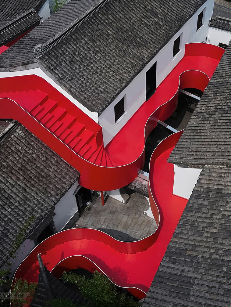archpng's tweet photo. A bright red architectural ribbon cuts through the historic rooftops of Nanjing.

Designed by Dayi Design, Red Lobster / Big Red Crayfish is a renovation project in the Qinhuai River district, one of the city’s oldest cultural areas. Instead of turning the existing buildings into untouchable relics, the project reactivates them as a contemporary dining and commercial space.

Its most striking feature is the sinuous red steel stairway that winds through the courtyards, linking separate historic buildings into one continuous route. The vivid red intervention creates a sharp contrast with the white walls and grey tiled roofs, but it also gives the old complex a new public life.