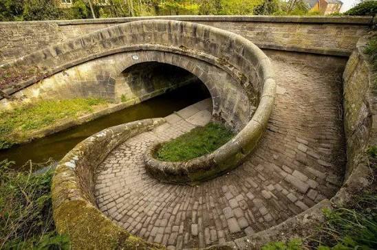 WolfofX's tweet photo. This spiral bridge on England's Macclesfield Canal is an impressive example of 19th-century engineering. Known as the "Snake Bridge" or "Roving Bridge," it was created to let horses towing canal boats switch sides of the canal without needing to be unhitched from the towline. https://t.co/Yibe4IZo4a