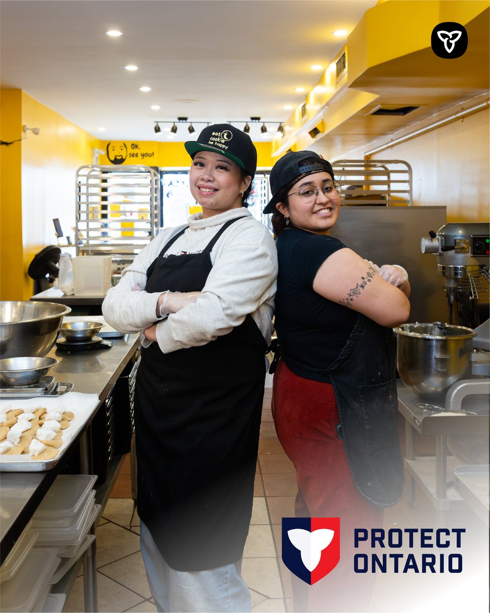 Two bakers smiling back to back.