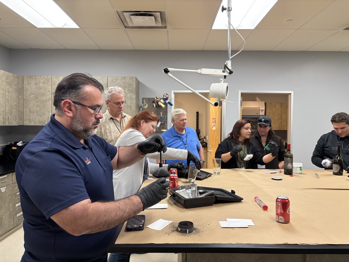 A group of people standing in a crime lab learning to extract fingerprints.