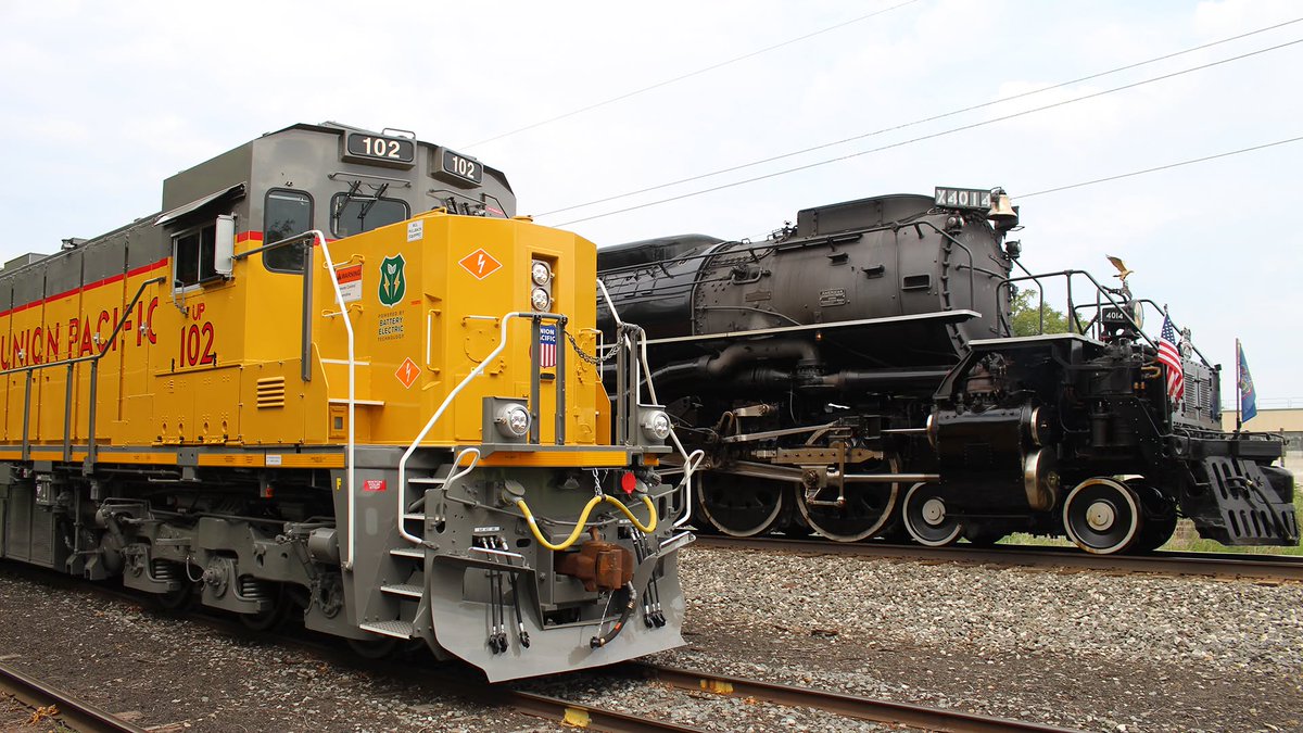 UnionPacific's tweet photo. A historic meetup as innovations from the 20th and 21st centuries met in Erie, Pennsylvania. Big Boy #UP4014 was built to haul increasing volumes of freight efficiently over the mountains during World War II, while @WabtecCorp's newest #FLXdrive battery-electric locomotive is designed to move freight within rail yards more sustainably.