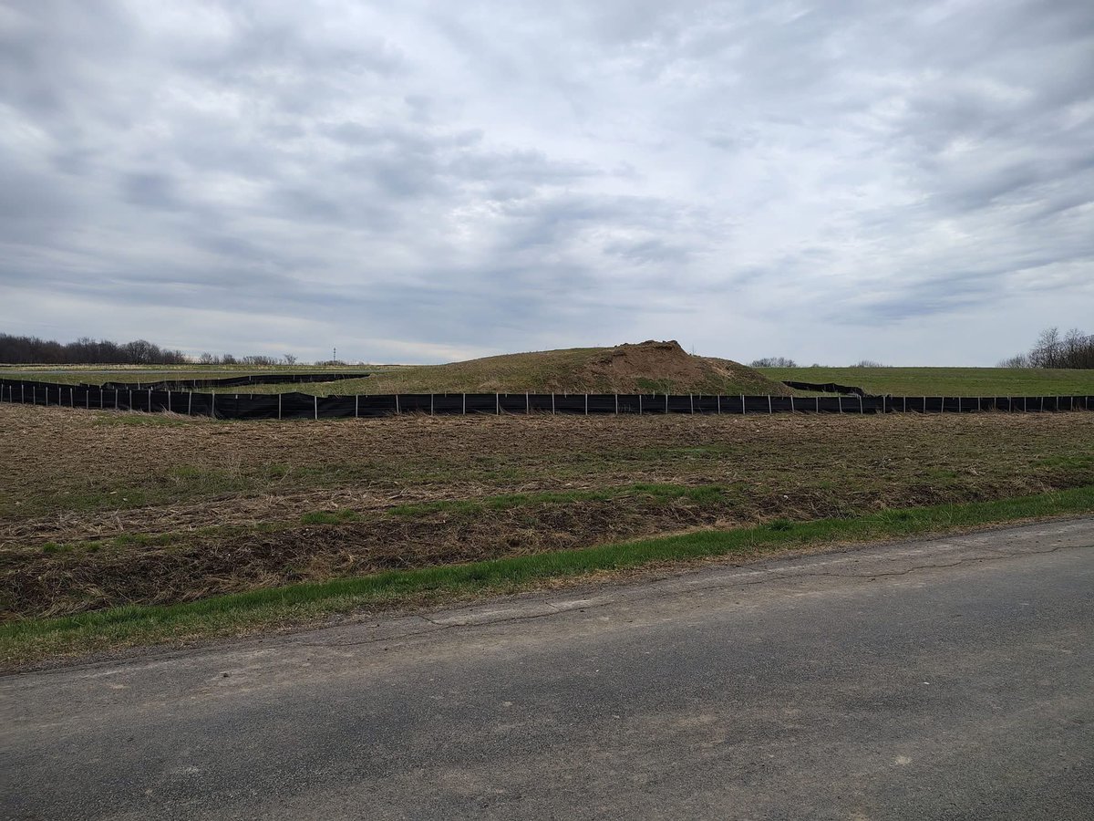 alex_fasulo's tweet photo. Here's the reality of a solar complex out in Byron, New York, where topsoil has been stripped, bulldozed, and piled across the street from solar arrays that are sitting in standing water.

Drainage retention ponds have been dug to spoil the natural drainage of the fields. Looks like they're doing a really great job of keeping that water drained!

That's what happens when you remove a land's topsoil and compact the ground below it. It's also what happens when you remove natural grasses and native plants that have 6 to 15 foot long root systems. Everything floods.

It takes 600 to 1,000 years for 6 inches of topsoil to form. These commercial solar builders strip the land of that topsoil and dump it in a pile, pictured below. They don't "spread out the soil" or reuse it elsewhere. Anywhere you've read that is utopian propaganda that does not exist at a single ORES solar complex in Upstate New York.

This is what these industrial zones look like instead. All for pathetic amounts of power that are unreliable, intermittent, and inaccessible when we need it most during the winter.

Your electric bill hasn't gone down. In fact, it's going to keep going up. The state needs billions of dollars to court these foreign developers with subsidies, credits, contracts, and promises. 

This is the biggest scam ever peddled on the American public.

This land will never be farmed again.