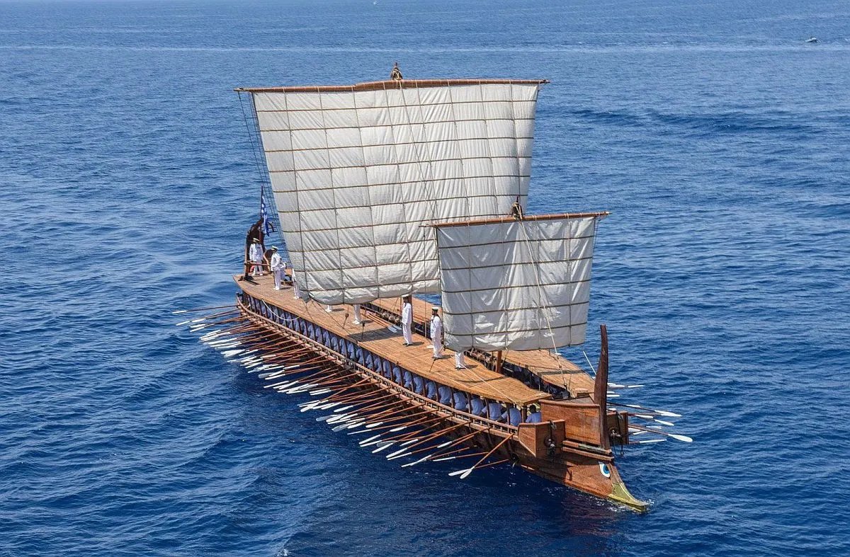 AncientHistorry's tweet photo. The sound of a trireme could be heard from a great distance. It had a rhythmic, measured quality, resembling a distant drum. Each stroke produced two distinct sounds: a deep, percussive thud of wood hitting water, followed by a rushing surge. Whumpff! Whroosh! These sounds were so familiar to the Greeks that they had specific names for them. They referred to the splash as pitylos and the rush as rhothios. The beat reverberated across the water, drawing the ships nearer. The steady, pulsating rhythm, was akin to the heartbeat of a giant.

Soon, other sounds emerged in sync with the oar strokes: the shrill, musical notes of pipes, the rhythmic commands of the coxswain encouraging the crew, and the deep chants of the rowers. The ship itself added to the cacophony, with its lumber and rigging creaking and groaning. As the triremes surged ahead, the steering oars and bronze rams hissed like snakes as they cut through the water. In the final moments, as the red-rimmed eyes on the prow fixed their gaze on you, the oar strokes resembled thunder. Then, the ship either bore down on you or veered away in search of other targets.
