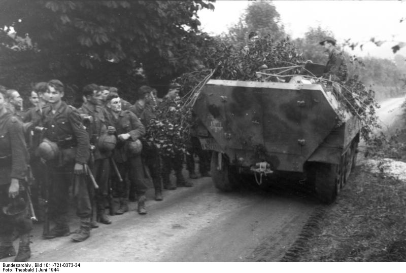 VoicesofWW2's tweet photo. A camouflaged SdKfz. 251 halftrack vehicle passing a column of German troops, France, Jun 1944 https://t.co/8qxwIiomrB