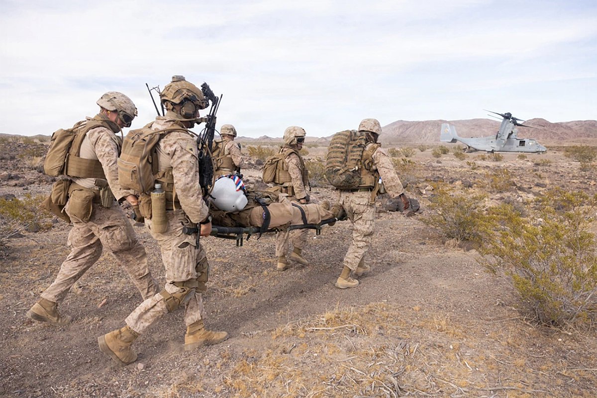 Marines carry a simulated casualty on a litter toward a MV-22 Osprey during a recovery mission exercise.