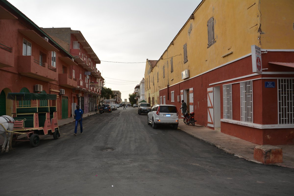 MadembAS's tweet photo. Par un 11 juin au Sénégal : Quelques lignes ajoutées à mon post du 11juin 2025 !

11 Juin 1958 : Transfert de la capitale du Sénégal de Saint-Louis à Dakar. Malgré les réserves du ministre de la France d’outre-mer Gérard Jacquet, le Président du Conseil de gouvernement Mamadou DIA avait pris cette décision pour des raisons stratégiques.

🇸🇳 Mamadou Dia, Saint-Louis et la capitale perdue : au-delà des légendes

Pas de panique ! Je ne vais pas appeler mes jarbaat, Doomu ou Dolli Ndar, à renouveler les manifestations du jeudi 1er août 1957, organisées pour protester contre la décision de transférer la capitale du Sénégal de Saint-Louis à Dakar !

Abdou Diouf décrit bien ces protestations avec les meetings dirigés par Babacar Sèye, ainsi que le sort réservé à Amadou Karim Gaye, alors directeur des services vétérinaires du Sénégal. Après un discours remarqué contre le transfert, Amadou Karim Gaye fut sanctionné dès le lendemain par un télégramme de Mamadou Dia le remettant à la disposition de la République française. Cela n’empêcha pourtant pas Mamadou Dia de le nommer ministre en janvier 1959 !

On rappelle encore cette phrase attribuée à Me Babacar Sèye, prononcée au pied ou sommet de la statue de Faidherbe : « Si Faidherbe était encore là, cette forfaiture n’aurait pas été décidée. »

Les manifestations firent plusieurs blessés, dont deux graves, et provoquèrent le saccage de trois maisons de ministres (Peytavin - Finances ; Édouard Diatta – TP et Transports ; et Amadou Bâ- Santé?)

Comme quoi, chers jarbaat, connaître les faits et gestes de vos grands-pères — et aussi de vos grands-mères, très actives à l’époque — peut vous aider à répondre, par un véritable VAR historique, à leurs sermons actuels de modération dans le jeu politique.

Si, dans l’imaginaire doomu Ndar, Mamadou Dia est l’unique responsable du transfert, la réalité est plus complexe. Le projet existait déjà sous l’autorité de Paul Cornut-Gentille, haut-commissaire de l’AOF de 1951 à 1956. Ses services avaient démontré que Dakar, par son poids économique et sa situation géographique, était plus adaptée au rôle de capitale du Sénégal. C’étaient d’ailleurs les mêmes arguments qui avaient conduit au transfert de la capitale de l’AOF de Saint-Louis à Dakar le 1er octobre 1902.

En contrepartie, Saint-Louis devait accueillir une université, l’Université de l’AOF, et devenir un pôle culturel et touristique. Naxee mbaay !

Le ministre de la France d’Outre-mer, Gérard Jacquet (1916-2013), socialiste, franc-maçon du Grand Orient et partisan du « Non » au référendum de 1958, se rendit à Saint-Louis en mars de cette même année. Il constata que la municipalité était opposée au transfert alors que l’Assemblée territoriale y était majoritairement favorable. Il réussit l’exploit de ne rien résoudre tout en mécontentant tout le monde.

Mamadou Dia, pragmatique, en tira immédiatement les conséquences : «Le respect des institutions démocratiques d’Outre-mer fait obligation au gouvernement de la République de promouvoir par décret la décision de l’Assemblée territoriale.» Dans le même temps, il s’engagea à installer l’ensemble des ministères à Dakar avant décembre 1958.

Le ministre français signa donc le décret transférant à Dakar « le chef-lieu du territoire du Sénégal », conformément au Journal officiel du 11 juin.

En réalité, le principe du transfert avait déjà été arrêté le 30 juillet 1957 par le gouvernement du Bloc Populaire Sénégalais, malgré l’opposition de Lamine Guèye, alors maire de Dakar et ancien maire de Saint-Louis (Il aurait même pu être maire de Bakel ou de Médine, où réside encore une partie de sa famille, m’avait glissé un véritable historien — celui-là !)

Ndeysaan, Dakar deviendra non seulement la capitale du Sénégal, mais accueillera aussi son «Ndar gu ndaw» à Ouagou-Niayes, le quartier de votre Nijaay mon ami Mouhamadou Tidiane Kassé, l’un des premiers utilisateurs au Sénégal de PageMaker sur Macintosh pour réaliser Sud Mag puis @sud_quotidien  et @walfadjrisn.

Plus sérieusement, certains estiment que ce transfert répondait également à une logique stratégique : éviter un scénario à la comorienne, comme celui de Mayotte en 2009, où une partie du territoire aurait pu être tentée de réclamer un maintien dans l’ensemble français sous l’influence de certaines autorités traditionnelles de la République Leebu de Dakar (un petit entretien sur cette question avec le Grand Serigne Dakar Ablaye Maxtaar me plairait bien même si je dois lui envoyer d'abord du pain 😃 !).

Tout Saint-Louisien a entendu, dans sa famille, parler du fameux « coup de Dia pour tuer Ndar ». Pourtant, dès le 20 juin 1958, Mamadou Dia présidait lui-même une commission ad hoc chargée d’élaborer un plan de développement pour Saint-Louis. Celui-ci prévoyait notamment la création de la Délégation de la vallée du fleuve Sénégal, regroupant Saint-Louis et cinq circonscriptions administratives.

La dénonciation par le Sénégal de l’accord sucrier de l’OCAM, qui permit plus tard la création de la Compagnie Sucrière Sénégalaise, peut également être vue, indirectement, comme une forme de compensation économique après le transfert.

Mais ce sont surtout les initiatives privées qui continuent aujourd’hui de faire rayonner Ndar : le Festival international de jazz, les Deux Rakas de Cheikh Ahmadou Bamba, les gamous d’Alaaji Maajor, de Seriñ Seex, de Xalifa Ababacar, de Jakk Wolof à Tengijéen, de Habib Sall à Balakos sans oublier les tabala xadr, ainsi que le travail remarquable de @_AmadouDiaw qui booste l’attractivité de la ville.

Tout cela contribue à faire de Saint-Louis un patrimoine mondial exceptionnel, dont la fragilité écologique devrait logiquement exclure toute implantation pétrolière ou gazière lourde sur son territoire.

Alors, qui écrira un jour Mamadou Dia et les Saint-Louisiens : essai sur les relations complexes entre les Domu Ndar et l’élite politique allogène?

La regrettée mère d’Awa et de Mamie Cissé aurait sans doute été toute désignée pour cette tâche. En son absence, la mission revient-elle à Mame Penda Bâ de @UGBSN , si ses nouvelles fonctions de directrice du Financement des établissements d’enseignement supérieur lui en laissent le temps ?
Ou peut-être que l’ouvrage existe déjà et que je ne suis tout simplement pas au courant. Ce qui est tout à fait possible !

#
 
11 Juin 1900 : Décès à Dakar à l'âge de 38 ans de Monseigneur Joachim Buleon, Vicaire apostolique de Sénégambie. Son successeur, Monseigneur Alphonse Kunemann, n'arrivera à Dakar que le 24 juin 1901.

🇸🇳 🇫🇷 Monseigneur Joachim Buléon avait été en poste à Saint-Louis de 1884 à 1886 — donc bien avant le transfert de la capitale par Mamadou Dia 😃 — où il apprit l’arabe et le wolof. Mais, de santé fragile, il fut rapatrié en France. Désireux de revenir en Afrique, il obtint une nouvelle affectation et fut nommé supérieur de la mission de Ngasobil, qui accueillera plus tard Léopold Sédar Senghor.

Travailleur infatigable, il s'intéressait également au développement agricole des missions, contribuant notamment à l'essor de bananeraies et de rizières irriguées. En reconnaissance de son action, il fut nommé par le Saint-Siège, le 6 juin 1899, vicaire apostolique de la Sénégambie. Lorsqu'une épidémie de fièvre jaune frappa le Sénégal, Mgr Buléon en fut l'une des premières victimes. Il décéda le 13 juin 1900 — et non le 11 — à seulement 38 ans (Source : The Hierarchy of the Catholic Church).

Mgr Kunemann, quant à lui, aimait parcourir son vaste territoire pastoral afin de rester proche de ses ouailles. Mais, alors qu'il revenait de Ngasobil vers Dakar, le navire sur lequel il voyageait fit naufrage en mer, entraînant sa disparition ainsi que celle de l'équipage.
Il a laissé plusieurs écrits sur les missions catholiques du Sénégal dans des revues spécialisées, ainsi qu'un ouvrage liturgique intitulé Cérémonies et prières de la consécration des églises, publié à l'occasion de la dédicace de l'église du Sacré-Cœur de Ngasobil en 1885.

Une question demeure : ces ouvrages sont-ils conservés dans nos bibliothèques, qu'elles soient laïques ou religieuses, au Sénégal ? Voilà une recherche qui mériterait d'être menée.

Note : Comme mes jarbaat le savent, je ne suis expert en rien. En dehors de mes commentaires subjectifs, partiels, biaisés et précédés de 🇸🇳, ces informations sont disponibles sur des milliers de sites, notamment SenegalDates.

#11juin #Senegal #Kebetu