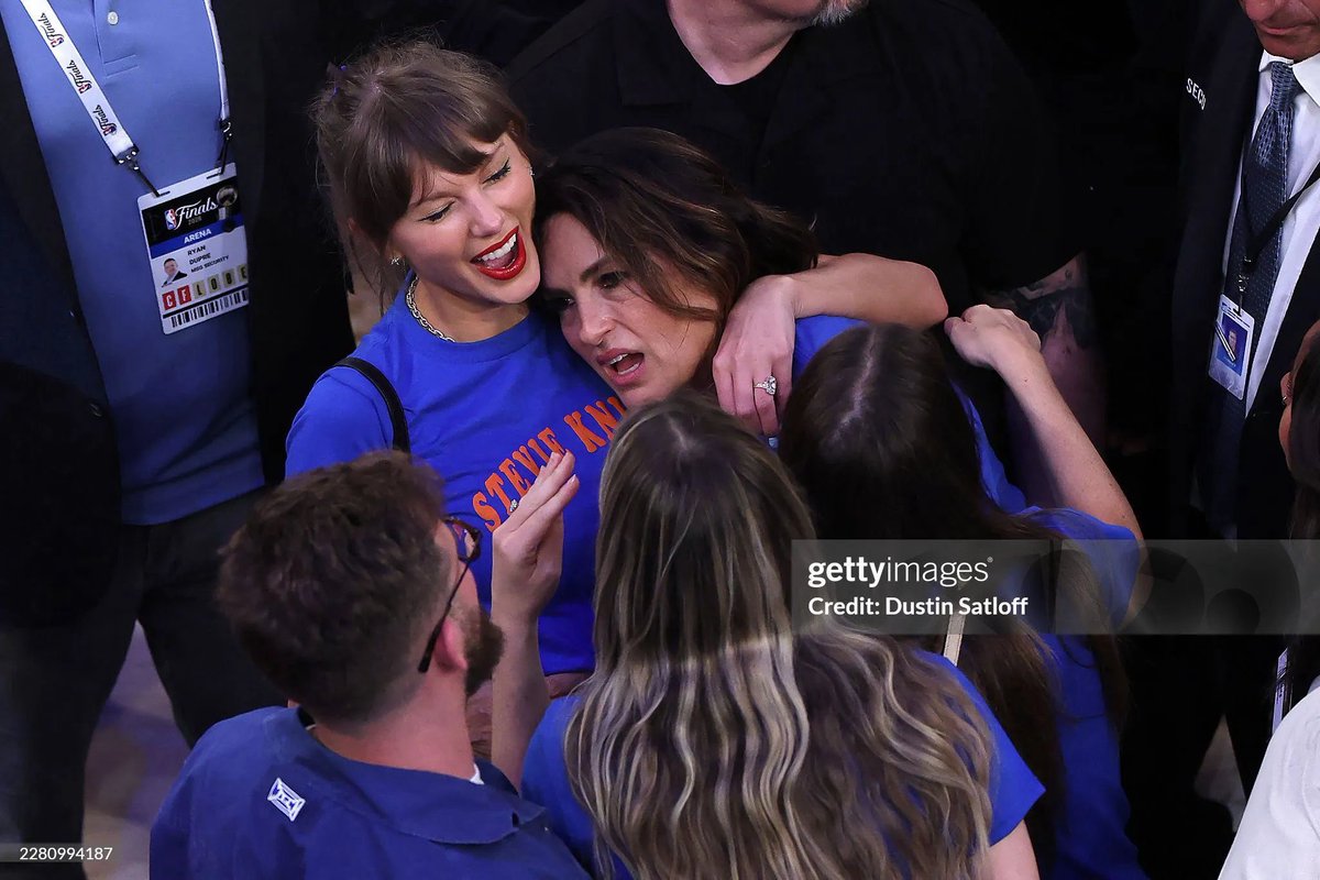 Mariska Hargitay looks distressed while a smiling Taylor Swift cradles her in a celebratory hug. This is a photo after the Knicks complete the greatest comeback in NBA history.