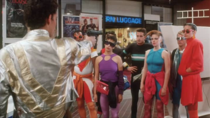 osunac's tweet photo. En "Remote Control" 📺 (1988) nadie viste discreto. Si un personaje cae en el control mental alienígena, se pone fosforito. Hay mallas de gimnasio 🤸♀️ y telas metalizadas que brillan más que el cartel del #videoclub. Una paleta cromática que te quema las córneas.
#80smovies https://t.co/dDtZ0xGN3L