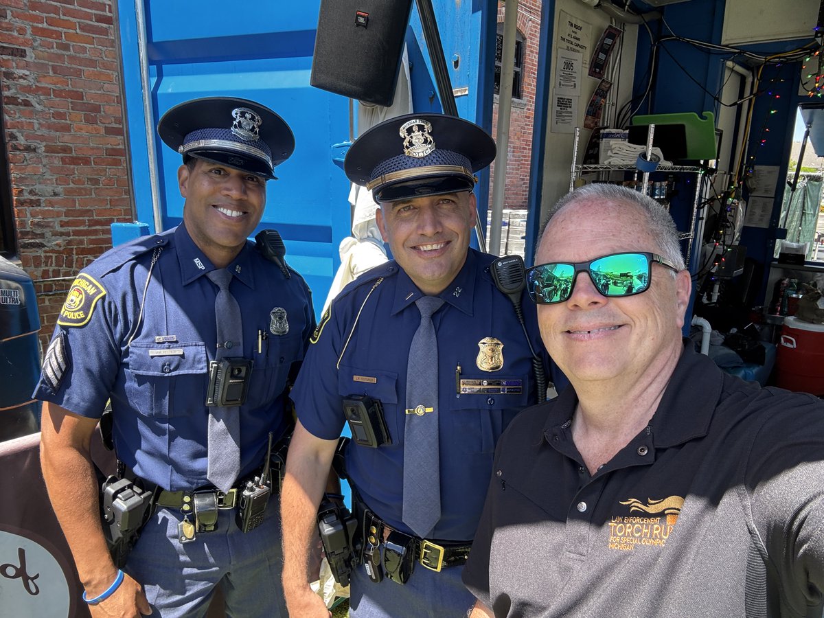 Two Michigan State Police troopers posing with a retiree outside in downtown Detroit as they helped escort the Flame of Hope and athletes making their way to the 2026 Special Olympic USA Games in Minnesota.
