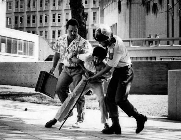 HistorySAZAR's tweet photo. Police detain Firoz Cachalia, a law student, during protests at Wits University in Johannesburg. The man on the left had earlier posed as a student. August 1985. Credit: Ismail Lagardien. https://t.co/Hggd7xq2to