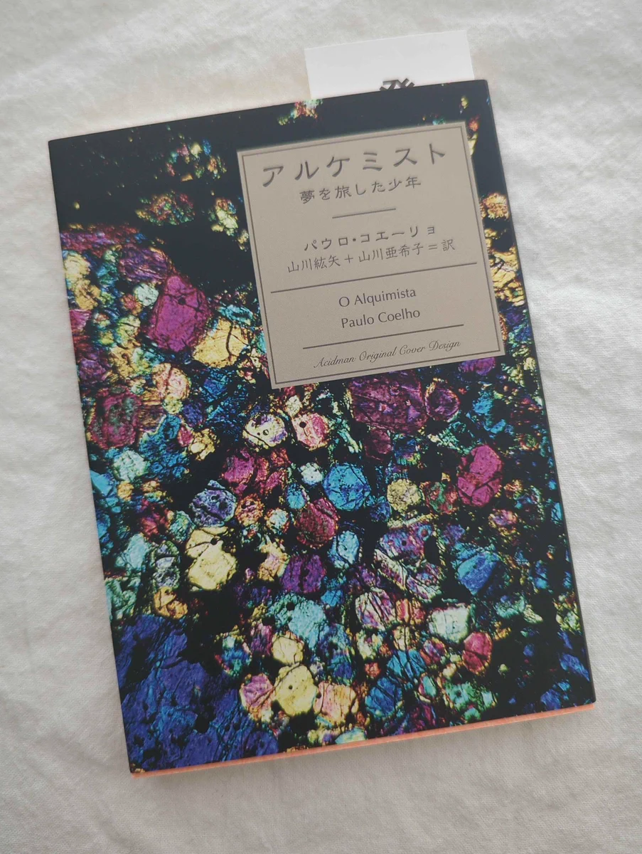 the book 「アルケミスト - 夢を旅した少年」or "o alquimista" by paulo coelho. the cover is ACIDMAN's album art for their single 「アルケミスト」.