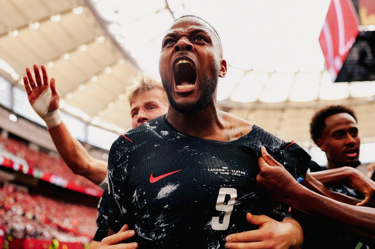 Cyle Larin celebrates scoring for Canada against Qatar at the FIFA World Cup with, wearing the black away kit.