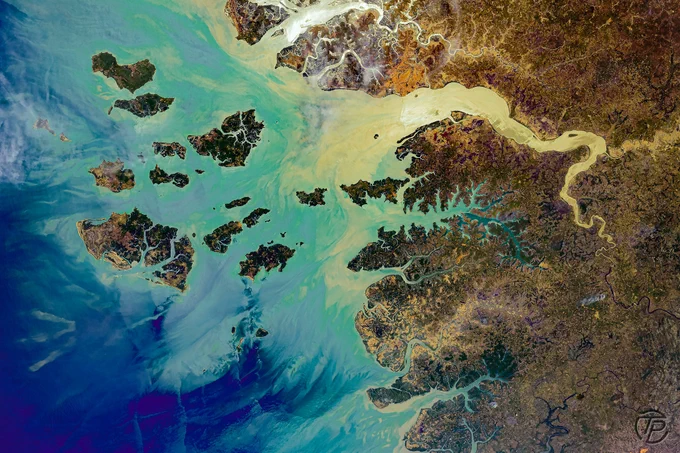 Vue prise depuis l’ISS de l’archipel des Bijagós, en Guinée-Bissau. Des dizaines d’îles sombres émergent d’eaux turquoise et bleu profond, traversées par des panaches de sédiments clairs qui dessinent des motifs fluides. Les mangroves, chenaux et embouchures forment un paysage naturel aux allures de peinture abstraite.
