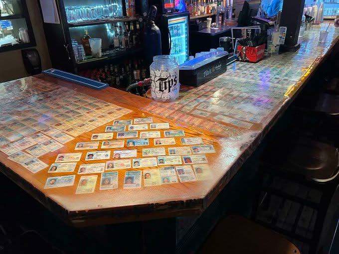 ThatEricAlper's tweet photo. This bar that decorated its bar top with the confiscated fake IDs of college students. https://t.co/NlcORTpTUK
