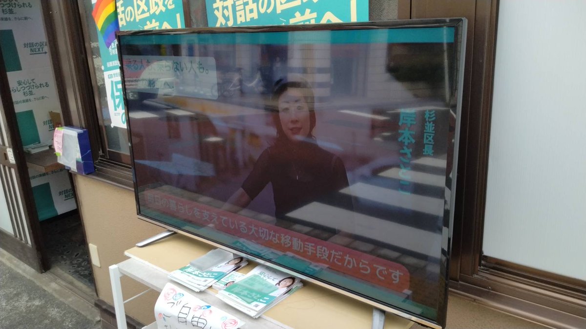 HirokoKado's tweet photo. 岸本杉並区長の西荻の新事務所の前のモニターが、公選法違反なのではないか？とうちの事務所にご意見や写真が送られてきました。
私からすれば、黒に近いグレーぽい、仮に黒でも形式犯ぽいですが、その辺の判断は当局の手に委ねられます。
岸本区長が、公職なのに法令ギリギリ（てかアウト？）、脱法行為というのはなかなかのストロングスタイルだなという感想です。

以下、私の理解です。

【岸本区長事務所前の公道に向けて外に設置した大型モニターは公選法違反か？】

① 公選法上、（選挙期間ではない）政治活動期間では、候補者等の氏名・氏名類推事項（顔写真・似顔絵等）を表示する文書図画の掲示には一定の制限がある。（政党等の政治活動を除きます。岸本区長は無所属と自称）
② モニター等によって表示されるものは、形態上はデジタルサイネージ（電子看板）と同様であり、公選法では看板類（立札・看板の類）と見なされる。動画もありますが、ずっと岸本区長の顔が出てる状態。
③ ①に制限されない②の看板類は、候補者等または後援団体の政治活動のために使用されるものに限定され（公選法143条16項1号）、実質的にそれは政治活動用事務所看板とされる。
④ ③の看板は1基が150×40cm以内のサイズ制限、候補者等・後援団体で各6枚ずつの枚数制限がある他、区市選管に証票の交付申請をし、その証票の貼付がない看板は掲示禁止となる。（公選法143条17項）

よって、岸本区長の氏名・氏名類推事項を表示するモニターは③の政治活動用事務所看板と見なされるが、④のサイズ制限オーバーの上、証票の貼付が認められないように見えることから、そもそも掲示できない看板類と指摘されうる。
（※なお、軒下の横型の事務所看板には証票が貼ってあります）