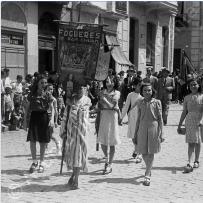 Postiguet_alc's tweet photo. Alacant, desfilada de comissions en 1942. Tot i la castellanització del franquisme, en la cartelleria oficial de les festes, per exemple, els foguerers alacantins van traure al carrer la simbologia que usaven abans de la guerra en llengua pròpia. https://t.co/90Z2nD3Zuv