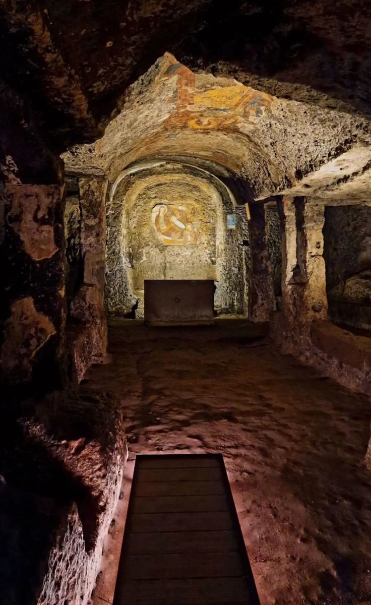 archeohistories's tweet photo. Church of Santa Maria del Parto in
Sutri: an Etruscan gem at the Gates of Rome, Italy 🇮🇹

Hidden among the forests of Tuscia Viterbese, Sutri is an archaeological and historical gem, this small village in northern Lazio preserves extraordinary evidence from various eras, from its Etruscan origins to Roman period and medieval age. Among the most evocative attractions in Sutri stands the Church of Santa Maria del Parto, a truly unique sacred site.

The church was created within an ancient Roman mithraeum, itself carved into the tuff of the same hill that hosts the amphitheater and necropolis. This extraordinary example of sacred space reuse tells the story of the transition from paganism to Christianity: where once the mysteries of the god Mithras—an Eastern deity particularly popular among Roman soldiers—were celebrated, now stands a Christian place of worship dedicated to the Virgin Mary.

This cave church which was dug into soft tufa during 13th-14th Century AD. But it is also called Mitreo di Sutri (Mithras Grotto of Sutri) which seems rather strange at the first glimpse. Explanation is simple though: archaeologists found numerous remains which are typical for the underground place of worship of the god Mithras. The estimated age is 1st-2nd Century AD. Later the Roman empire became Christian, and old temples were abandoned. In this cave it was abandoned for a thousand years, then the place was converted into a christian cave. They changed some details, like doors and windows, and they added the apsis, but the rest is almost original the much older Mithraeum. The floor still contains the Mithraic baptismal font where believers were initiated into the Mysteries of Worship with a water baptism. Baptism was not invented by Christianity, actually. Mithraic Taurobolium was removed in 4th Century AD, and was reused to build a farmhouse on the Via Cassia, in the hamlet of La Botte. If you go there, it is clearly visible on the wall of building a few metres from the road. It shows god Mithras wearing a Phrygian cap, in act of killing the bull (tauroctonia) while a scorpion attacks the bull’s testicles.

The door is rectangular and today has two wooden doors and a glass window over the doors. The tufa wall was obviously quarried to form a sort of flat facade, which contains numerous holes which were needed for wooden beam, some sort of wooden building in from which is now completely gone. There is also a triangular line, which is from a roof above the door. After entering through the door, a square vestibule is reached, where frescoes depict Madonna and Saints, St Christopher and events linked to life of St Michael of Gargano. Then the main room follows, rectangular with three naves, divided by ten pillars on each side. The pillars have a sort of basement which forms a sort of steps on both sides of the main nave. The central nave has a barrel-vaulted ceiling. The two side naves are only about 1 metre wide and have flat ceilings. The apsis on the far end is also rectangular and shows the remains of frescoes depicting the Nativity, which explains the name of the church.

The interior of the church features three naves separated by pillars carved directly from the rock. The walls preserve important medieval frescoes, among which a seated Madonna with Child stands out (from which the name “del Parto,” or “of the Childbirth,” derives), dating back to 12th–13th Century AD. Other frescoes depict scenes from the life of Saint Christopher and episodes related to Saint Michael of Gargano.

What makes this place so special is its almost mystical atmosphere, enhanced by the soft light that filters inside and the profound silence that envelops the space.

#archaeohistories