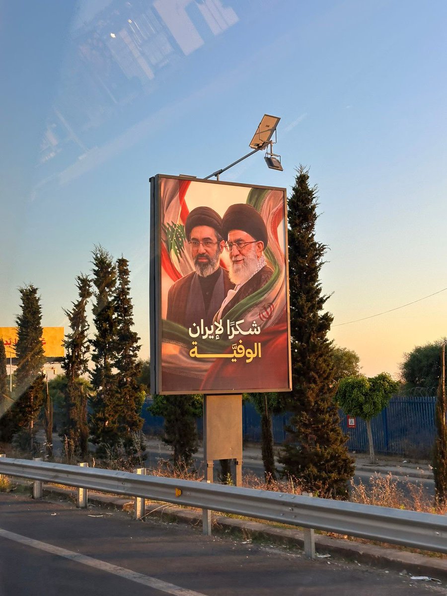 hahussain's tweet photo. One of the first things that President Aoun and PM Salam did after their election was that they cleaned up the road to the Beirut airport by taking down all of Hezbollah’s Iran propaganda posters. 

Today, Hezbollah is signaling to the Lebanese government that it’s back. The militia put up a poster of Iran’s dead tyrant Khamenei and his successor with the comment: Thank you Iran. 

There will never be peace in the Middle East without the collapse of Islamic Iran regime.