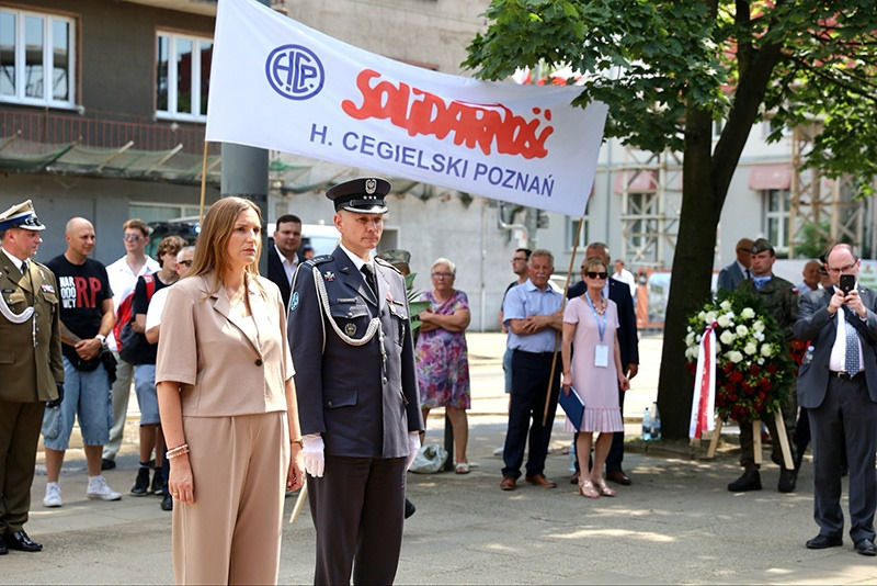 MKurzejewski's tweet photo. Szacunek za udział w uroczystościach, ale z jakiego powodu przerobiła Pani zdjęcie (załączam oryginał) w AI żeby usunąć napis "Narodowcy RP" na koszulce mężczyzny, który stoi za Panią? https://t.co/1BD4YHOWV0