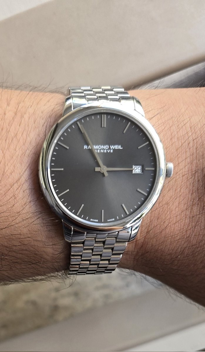 OnurWsC's tweet photo. Raymond Weil Toccata 42mm Quartz RW5585ST60001

Her mekanik severin zor zamanları için tuttuğu bir quartz saati vardır. Bu saat hem inceliği ve sadeliğiyle klasik ve dress konseptine uygun olup hem de gündelik kullanımda da kullanışlıdır. Saniye ibresinin bulunmaması, mekanik saat takıntısı olanlar ve quartz saatin saniye ilerleyişini beğenmeyenler için kurtarıcıdır.

Saat; 42mm kasa çapı ve 6mm kasa kalınlığıyla geniş bilekli olan ancak hafif ve ince bir saate sahip olmak isteyenler için kurtarıcıdır.

Modelin kasası, korozyona dirençli 316L paslanmaz çelikten üretilmiştir. Kasa profili, bilekte konforlu bir oturuş sağlamak üzere ince ve dengeli tasarlanmıştır. Bezel ve boynuzlardaki polisaj işçiliği, parlatılmış yüzeylerin zarifliğini başarılı bir şekilde yansıtır.  Saatte çizilmeye dayanıklı safir cam kullanılmıştır. Ancak  camda olan yansımadan anti refle uygulamasının bulunmadığı veya tek taraflı ve zayıf şekilde iç katmanda uygulandığı izlenimini uyandırmaktadır. Bununla birlikte sade ve harejetsiz kadranın yansımayla birlikte daha eğlenceli bir hale geldiğini de söylemek mümkündür.