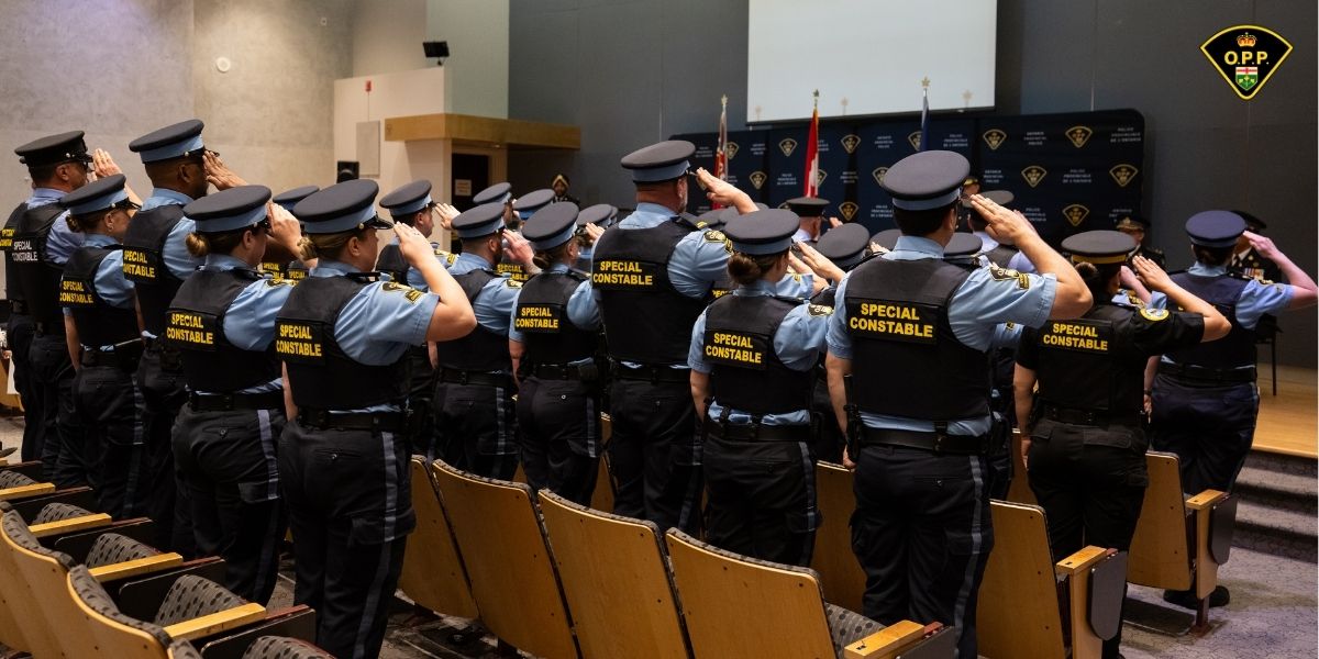 OPP Special Constable graduates stand at attention, saluting the stage during graduation ceremony.