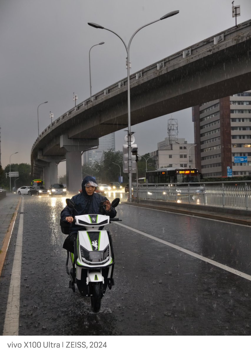 Foggy380's tweet photo. [Rainy afternoon, city street vibes—wet pavement glows under neon, a cyclist zips past with a hood up. Little moments make the best shots ]， https://t.co/EsNNgxNxqa