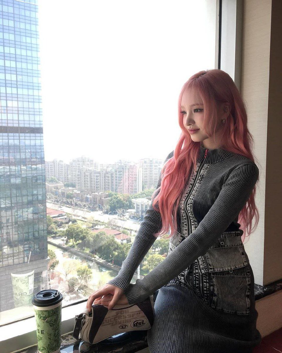 kimjizwon's tweet photo. With a paper of sweetness in my hands and the evening breeze dancing through my pink hair, I linger on the balcony where the sky slowly melts into shades of gold and lavender. The city hums softly below, while my heart drifts among clouds painted by the setting sun. https://t.co/mQAA1MksoS