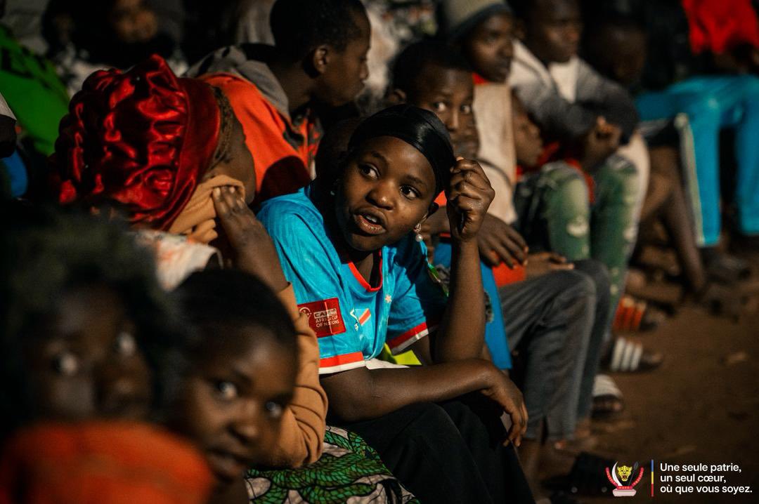 michombero's tweet photo. #Kinama : à l’aube glaciale de l’exil, les réfugiés congolais vibrent au rythme des Léopards

Il est à peine 4 heures du matin lorsque les premiers réfugiés congolais commencent à converger vers le site de retransmission installé au camp de Kinama. Malgré le froid mordant qui enveloppe les collines du nord-est du Burundi, des centaines d’hommes, de femmes et d’enfants se mobilisent pour suivre le match de Coupe du monde opposant la RDC à la Colombie.

Munis de chaises, emmitouflés dans des couvertures ou vêtus des couleurs nationales, dans le cadre d’un bon voisinage, d’autres Burundais qui supportent les Léopards parcourent parfois plusieurs kilomètres à pied pour vivre ce rendez-vous avec la sélection nationale. Dans ce camp qui accueille plus de 6000 Congolais ayant fui les violences dans l’est de la RDC, l’événement dépasse largement le cadre sportif.

Avant le coup d’envoi, l’ambiance est marquée par les chants, les pronostics et une grande ferveur patriotique. Chaque action des Léopards est suivie avec passion, chaque occasion suscite l’espoir d’un exploit face à la Colombie.

Malgré la défaite congolaise (1-0), les réfugiés ne cachent pas leur fierté. Très vite, les discussions se tournent vers le prochain match contre l’Ouzbékistan. Pour beaucoup, l’essentiel était ailleurs : se retrouver, partager un moment d’unité et rester connectés à leur pays d’origine.

Au camp de Kinama, cette nuit a une nouvelle fois démontré la résilience des réfugiés congolais. Loin de leur terre natale, mais toujours attachés à la RDC, ils ont rappelé que l’exil n’efface ni l’identité, ni l’espoir, ni l’amour de la patrie.