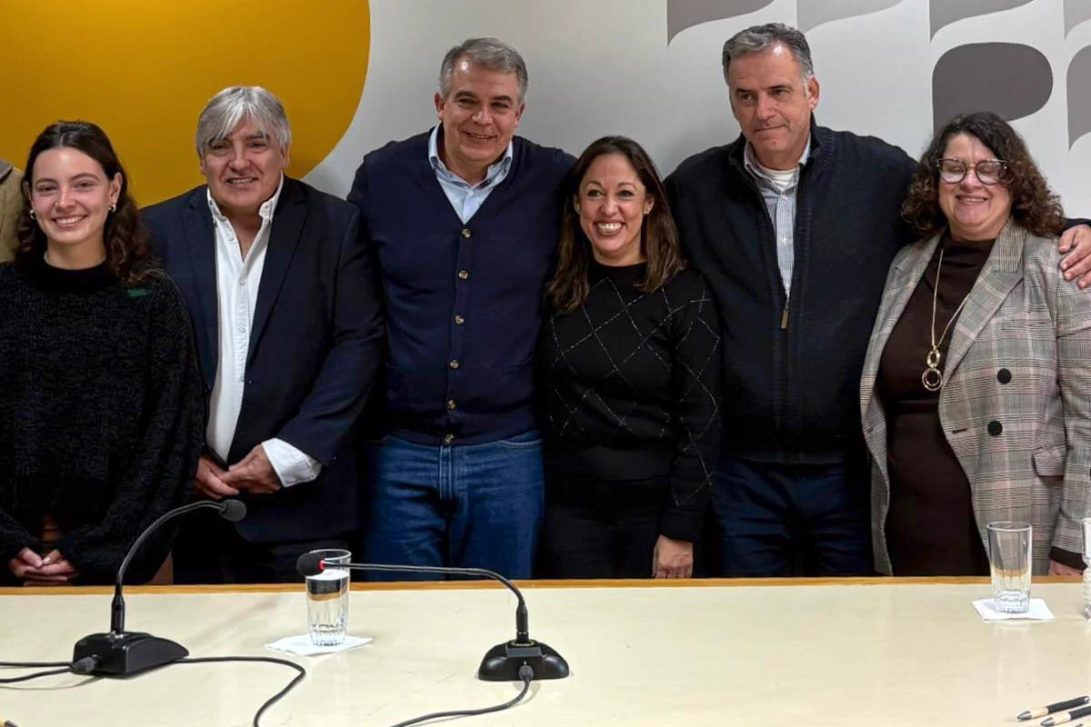 Autoridades sonríen, de pie, detrás de una mesa.