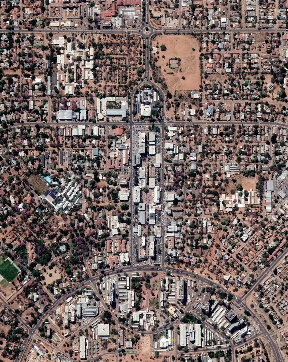 NestorSiurana's tweet photo. La ciudad de Gaborone, en mitad del desierto, es increíble desde el cielo.

La capital de Botsuana tan sólo cuenta con una población cercana a los 250.000 habitantes.

Concentra la actividad administrativa, financiera y comercial del país.

Fundada en la década de 1960 para convertirse en la nueva capital tras la independencia, Gaborone es una de las capitales más jóvenes de África.

Ha experimentado un crecimiento sostenido impulsado por la estabilidad económica del país y el desarrollo asociado a la industria minera, especialmente la extracción de diamantes.

El núcleo original de la ciudad se edificó desde cero en un tiempo récord de solo tres años. En ese breve período se levantaron el parlamento, los edificios gubernamentales, un hospital, varias escuelas y más de mil viviendas.

Desde el punto de vista urbano, Gaborone presenta una condición interesante.

A primera vista, la ciudad parece poseer un trazado heterogéneo, con barrios, vialidades y áreas de expansión que no responden a una única lógica geométrica dominante.

Sin embargo, al observarla con mayor detalle, es posible identificar que gran parte de la mancha urbana está compuesta por una sucesión de unidades planificadas de menor escala, cada una con su propia organización interna de calles, espacios públicos y equipamientos.

Esta estructura genera una especie de mosaico urbano donde distintos sectores presentan retículas, supermanzanas o configuraciones curvilíneas claramente definidas.

El resultado contrasta con muchas ciudades africanas que crecieron de manera más espontánea u orgánica alrededor de núcleos históricos, ya que en Gaborone la planificación moderna es visible en numerosos fragmentos de la ciudad, otorgándole una identidad urbana singular donde la diversidad formal surge de la suma de múltiples desarrollos planificados.