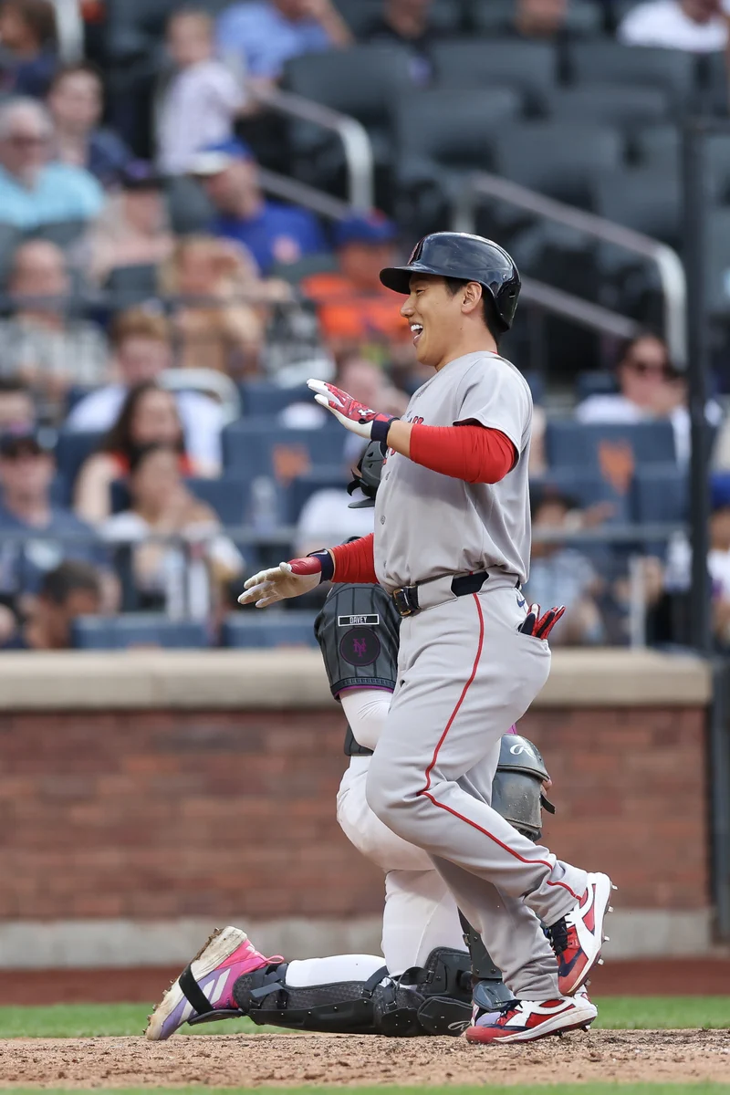 Masataka Yoshida celebrates and smiles while crossing home plate after hitting a home run at Citi Field. He is wearing the Red Sox road grey uniform.