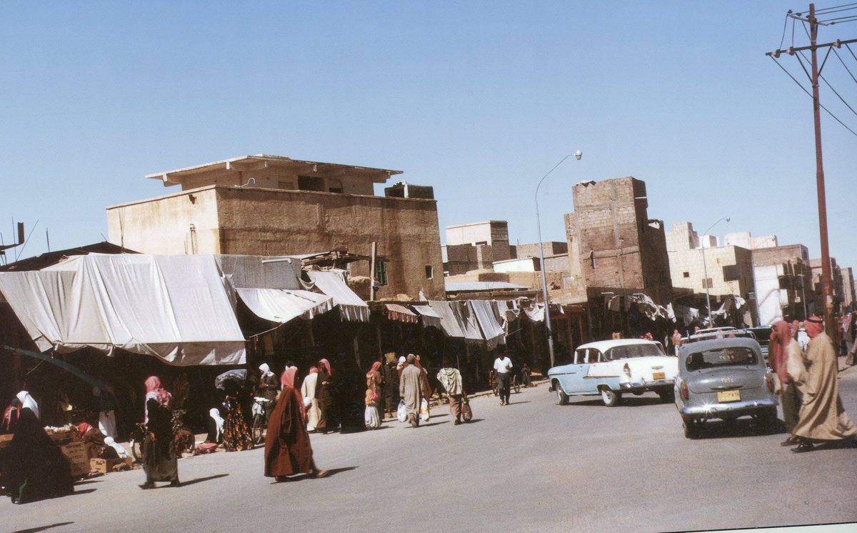 DrMalowein's tweet photo. قرويٌ في الرياض قبل ثمانية وخمسينَ عاماً

الديرة، دخنة، سويقة، الصفاة، شارع الثميري، سوق السدرة، مليحة، سوق الزل، القري، وشيقر، المقيبرة، شارع الوزير، شارع السويلم، شارع الظهيرة، معكال، الشميسي القديم، الشميسي الجديد، دوار أم سليم، شارع سلام، جبرة، العجلية، شارع الغنم، الأعشى، دويرا سلام، طريق الحجاز القديم، منفوحة، البطحا، الطويلعة، البديعة، شارع الخزان، حديقة الفوطة، الناصرية، الملز.

.. هذه بعض أسماء شوارع وأحياء #الرياض_القديمة التي كانت تشكل المدينة الصغيرة ربما خلال أكثر من ثلاثة قرون من الزمن.

كانت الرياض لا تتجاوز هذه المسميات في الثمانينيات الهجرية من القرن الماضي، وما حولها من كل الجهات براري وصحاري واسعة ممتدة، يخرج إليها أهالي المدينة للنزهة وللفرجة وكأنهم يقصدون سفرا بعيدا! مثل خريص، وصلبوخ، وديراب، والواشلة وغيرها.

كانت الحياة في الرياض القديمة لها مذاقٌ خاصٌ، ولشوارعها ودكاكينها وأسواقها وبيوتها المبنية من الطين أو تلك التي لامستها يد الحداثة فبنيت من البلك وأضيئت بالنجف الأزرق نكهةٌ خاصةٌ وصورةٌ في المخيلة لاترتسم ولاتنبلج إلا حين تُذكر الرياض، أو تُطل الرياض بمعالمها القديمة مع أول شارع يستفتحها من جهة الجنوب، وهو شارع منفوحة..!

للمدينة آنذاك بساطتُها الخاصة، ولها جمالٌ لا يمكن أن يتكشف سافراً إلا مع تباشير الصباح المشرق الهادئ؛ حيث لكل شيء فيها لون وطعم ومذاق مختلف عن القرية، ولأحاديث الناس ولكنتهم، وحروف اللغة المخففة الممطوطة قليلا على ألسنتهم وقعٌ آخرُ مختلفٌ أيضاً في أذن قروي جاء من حروف كبيرة ضخمة فخمة تنزل على الأذن دفعةً واحدةً بدون تمطيط ولا إمالة!

لأول مرة مطلعَ عام 1389هـ يقدم فيها هذا الفتى القرويُ إلى مدينة الرياض في صباح يوم ربيعي زاهٍ وجميل، وما نام البارحة ولا فارقته خيالاتُ الرياض التي يسمع بها من أقرانه ولداته ومن أسعفهم الحظ بالتمتع برؤية المدينة الحلم؛ فكان يُركّب مشهداً سمعه من سعد، ومشهداً من علي، وثالثاً من راشد، ويخلط تلك المشاهد ثم يعيد بناءها كيفما شاءت له مخيلتُه الواسعةُ القادرةُ على التفكيك والجمع، والمعتادةُ في مثل ساعات الليل الطويلة تحت أشعة النجوم الساهرة المراقبة على توليد عشرات الصور، وعلى خلق حيواتٍ وقصصاً من كل شكل ولون.

ليلٌ طويلٌ لايكاد ينقضي إلا حينما لكزه أبوه في فجر ذلك اليوم ليستعد للسفر ويستطعم ما تيسر من مخبز يحيى اليماني الذي كان يبيع ثماني خبزات بريال تفوح رائحتها النفاذة طوال الطريق إلى المنزل مع أنها مندسةٌ في كيس من البلاستيك له عروتان طويلتان يأخذه معه تحت إبطه وهو ذاهب لصلاة الفجر، وغمس الفتى على عجل نتفاً من الخبز في كأس حليب «أبو قوس» ولم يكد يدفع جوعه حتى تحاشر الذاهبون إلى المدينة في بيجو أبي علي فكانوا ثمانية أو يزيدون، وبدأ والد الفتى يتلو في صوت لايكاد يسمع آيات من القرآن، وأدعيةً تتشارك مع انبلاج الصبح في كثير من الأمل والفأل الحسن والتيسير للأمور، وتسهيل الطريق البري الطويل الخالي من الشجر من الحياة والأحياء..

لم يلفت نظره قبل الدخول إلى المدينة إلا لوحات الدعاية الكبيرة المنصوبة على جانبي الطريق، فيقرؤها كلمة كلمة، ويتأمل صورها وألوانها، ويحفظ عباراتِها الموجزةَ الدالةَ بعمق على السلعة، ويعجب لماذا يحرص التجار على الإشارة إلى بضائعهم على هذا النحو من التكلف؛ فمن احتاج إلى شيء سيشتريه إن كان يملك ثمنه، فكان يرى في هذه اللوحات تزيُّداً وحرصاً على الربح لا مسوغ له، إلا أنها كانت تُسلِيه وتقطع عليه الطريق الذي لا يكاد ينتهي!

وهذا مصنع الإسمنت يبعث أدخنته إلى عنان السماء فيعلم أنه على وشك الدخول إلى المدينة كما سمع من قصص سعد وعلي وراشد، فيتهيأ ويعدل من تنبهه لئلا تفوته شاردة ولا واردة مما سيمر أمام عينيه من المناظر، سواء من المباني التي بدت غريبة عما ألفه في قريته من حيث الضخامة والتزيين، أو من حيث الشوارع التي بدت له وكأنه لا مثيل لها في السعة والامتداد، وما يحفها من أشجار، أو ما تنتهي به من إشارات ضوئية.

دخل بيجو أبو علي من شارع منفوحة الذي كان مزدحماً بالسيارات والبشر، وسمع قرقعةَ أغطية قوارير البيبسي تتناثر تحت عجلات السيارة، لم يعلم لمَ يشرب أهل الرياض كل هذه الكميات الهائلة من البيبسي! تساءل في قرارة نفسه، ثم انعطفت بهم السيارةُ إلى اليمين متجهةً إلى الديرة حيث ينزل معظم الركاب في موقف القرية المعروف، وهاله كثرة الدكاكين وامتلاؤها بالبضائع، وكثرة المتسوقين الذين لا تنقضي حوائجهم، وبدا له أن أهل الرياض أغنياء؛ بدليل ما يراه بأم عينيه من ريالات تصب في أيدي البائعين!.

للأزقة الضيقة بين البيوت الطينية العالية الارتفاع رائحةٌ كريهةٌ معروفةٌ تنبعث من بقايا الطعام ونفايات المنازل التي توضع مكشوفةً بجانب كل باب، فكان أبوه يضع طرف شماغه على أنفه محوقلاً إلى أن تبتعد الرائحةُ النفاذة وتختفي وسط نكهة حبات القهوة المقلية بعناية وهي تدور وتتقافز في مكينة الطحن بغرفة أخيه إبراهيم الذي لم تكد تسعه الدنيا حين سمع طرق باب غرفته ورأى والده وأخاه بين يديه.
 لأول مرة يرى الفتى نور الكهرباء النجف قويا ومشعا عن قرب، ولأول مرة يرى مكينة طحن القهوة الصغيرة ويسمع حنينها الخافت الذي لا يقطعه سوى جرش حبات القهوة ودورانها السريع وتكسرها وتطايرها داخل محبسها الزجاجي، ولأول مرة يرى جهاز التلفزيون الذي كان يبث صوراً بالأبيض والأسود لم يكد يتمعن فيها حتى سارع أخوه إلى إقفاله وإسدال غطاء عليه!.

تقف «الساعة» منتصبة شامخة في وسط ميدان الصفاة، وتدور حولها السيارات بدون ملل ولا كلل، وشرطي المرور يقف بينها وسط الغادي والرائح، ولا يعلم الفتى كيف يشير الشرطي بيده مرة يميناً ومرة شمالاً بصفارات متتابعة لهذا الفريق أو ذاك من قائدي السيارات فيعلم كلٌ طريقه ويفهم ماذا عليه أن يفعل، وأمام عينيه قصر الحكم ببنائه الأبيض الأنيق، ومن هذا الطريق المرتفع بجانب القصر تعبر سيارة حاكم الرياض #الأمير_سلمان بن عبدالعزيز إلى أن تقف مباشرة عند مدخل #قصر_الحكم، لقد سمع كثيراً من الحكايات والقصص المثيرة عن هذا الأمير، كانت المساءات في مجالس قريته تعمر بسرد حكايات مذهلة عن حزم الأمير وعدله وبصره العميق بالناس والقبائل، ومعرفته الدقيقة بالتاريخ والأنساب، وسعيه للتوفيق والصلح بين المتخاصمين، وتأييده ودعمه لتنفيذ الحدود الشرعية، كما كان شيوخ القرية يتحدثون بإعجاب عن ذاكرة الأمير العجيبة، وكيف أنه لو رآك لمرة واحدة لا يمكن أن ينساك أو ينسى اسمك أو ما تحدثت به، وسمع كثيرا من الحكايات عن كرمه وشهامته واندفاعه لعمل الخير فانطبعت صورته المميزة التي تنشرها الصحف في ذاكرة الفتى، وتساءل وهو يمد بصره إلى مدخل القصر: يا ترى لو جاء الأمير في هذه اللحظة والساعة تقترب من الثامنة صباحا وهو وقت مجيئه إلى مكتبه كما كان يسمع هل يستطيع رؤيته؛ بل هل يمكن أن يصافحه ويخلد هذه المصافحة في تاريخه ويتحدث بها بين أقرانه ولداته من أبناء القرية حين يعود؟! لقد شعر بشيء من القشعريرة حين تخيل الموقف: كيف يمكن لشاب قروي حدث بملابسه الرثة وتواضع هندامه وصغر سنه أن يحظى بشرف مصافحة حاكم الرياض؟! لقد تخيله بشخصيته المهيبة، وبطوله الفارع، وبنظراته الذكية الفاحصة؛ فتملكه الخوف، أو غشيته ساعة من قلق واضطراب! ولكنه حدث نفسه: كيف يستطيع «سلمان» - وهكذا ينطق الناس اسمه دون لقب - الإحاطةَ بكل ما يسمع عنه من قضايا ومشكلات؟ كيف لذاكرته مهما بلغت من قوة، وفراسته مهما بلغت من حدة أن يعرف الشاردة والواردة، وألا يدع صغيرة ولا كبيرة من هموم هذه المدينة وما يتبعها من مدن وقرى أخرى إلا بحث لها عن حل، وتتبعها جزءاً جزءاً مهما بلغت تعقيداتها حتى يصل مع أطرافها إلى حل مرض، أو يحيلها إلى الشرع ليبت فيها القضاء العادل.

ومثلما يستيقظ النائم أو يصحو الساهي تنبه الفتى من خيالاته البعيدة وأحلامه التي رآها متفائلة جدا، فمن يكون حتى يقدم نفسه للأمير؟ وهل يجد الأمير فسحة من الوقت ليستقبل شاباً قروياً يافعاً لا شأن له؟! ولكنه تذكر أن ساعة أو بعض ساعة - كما سمع من شيوخ قريته - تتاح لمن أراد السلام أو الشكوى، ولكن يا فتى كيف تحدث نفسك بما لا طاقة لك به؟ وما جدوى أن تعزم على الدخول إلى قصر الإمارة وأنت على هذا النحو من الرثاثة وتواضع الهندام وسوء المظهر؟ ألا ترى نفسك أيها القروي الصغير؟ انظر إلى غترتك البيضاء المحببة من الأطراف كيف تنطوي على كتفيك، وانظر إلى ثوبك الأبيض الدوبلين الذي يصدر صوتا مع كل حركة كالقرطاس، وانظر إلى نعلك المغبرة، وإلى وجهك غير النضر؟! كيف يدور في مخيلتك أن تحشر نفسك مع الداخلين وأنت رث نكرة مجهول غريب؟ فلترض من الغُنم بالتزود مما تفيض به هذه المدينة عليك من جديد المناظر والصور، وما تهديه إليك في كل ساعة من معارف وأخبار، وما تكتشفه من الغرائب التي لم تألفها في قريتك!...

                        ****************
يبدو الجو لطيفاً وربيعياً في الرياض القديمة مطلع عام تسعة وثمانين وثلاثمائة وألف، فما شعر الفتى بحرارة الشمس وهو يمد خطاه الكاشفة المتفحصة في ذهول بين ميدان الصفاة وقصر الحكم وشارع الثميري المزدحم بالمحلات التجارية، فمر من صيدلية شبيب المواجهة للساعة ورأى ما تخزنه من الأدوية وأدوات الطبابة فقال في نفسه: ما أكثر ما يمرض أهل الرياض! ثم رأى الأحذية معلقة ومصفوفة بانتظام خلف واجهات الزجاج، ورأى الذهب معروضاً في المحلات على قارعة الطريق لا يفصله عن المارة سوى حاجز زجاجي شفاف، فقال: ألا يخشى التجار على متاجرهم من اللصوص؟! كيف يعرضون ما لديهم مما يخف حمله ويرتفع ثمنه خلف زجاج فقط؟! فتمنى لو فاتح أحداً منهم في مخاوفه هذه، لكنه واصل سيره مكتشفاً؛ فوجد لوحة بسهم تشير إلى مدخل علوي يبدأ بدرج صغير ملتو، وقد كتبت لوحة صغيرة عند مدخل الدرج (استديو الرياض) فرأى أن يعرف ما طبيعة هذا الاستديو؟ وما شأنه؟ وماذا يفعل؟ فصعد الدرج الضيق الملتوي ولف لفتين فوجد نفسه في غرفة صغيرة تتصدرها مرآة وصور متعددة معلقة للملك عبدالعزيز وللملك سعود وللملك فيصل، فأعجب بحسن تنظيم وتوزيع الصور وسأل صاحبه: ماذا تفعل؟ فقال: أصور! قال الفتى: تعني تعكس؟! قال بلهجة يمانية واضحة: ايه تشتي تعكس؟ قال الفتى: بس زيّن عكسي! ألبَسه المصورُ جاكتة مخططة، ولا يعلم لم ألبسه الجاكيت مع أن الجو ليس بارداً، ولم هو أيضاً مخطط؟ ثم نزع غترته الملفوفة على عنقه والمنسدلة على كتفيه وألبسه غترة أكثر جدة منها لكنها موضوعة لكل الزبائن، ثم وضع على رأسه عقالاً وأخذ في موازنة مقدمة الغترة تحت العقال بحيث يبدو منها ثلاث كسرات وأمره بأن يبتسم وعيناه شاخصتان إلى بؤرة الكاميرا المنصوبة على ثلاث قوائم، ثم شع نور سريع خاطف، وبعد هنيهة شع نور آخر خاطف، وقال له الفتى: دعني أرى عكسي؟ فرد المصور: مالك يا فتى، تشتي تاخذها بعد ثلاثة أيام!

انتهت مغامرة اكتشاف هذا الاستديو، لكنه تساءل في نفسه: لم اختار مكانه في الدور العلوي؟ ولمَ لم يضع صوراً تدل عليه، ولمَ أخفى الصور داخلا، ولمَ لم يضع لوحة كبيرة؟ أفاده العارفون بأن وضع الصور الكبيرة خلف الزجاج أمام المارة في الشارع يعرض صاحب الاستديو لغضب بعض المتشددين!

والتفت يساراً وهو يخرج من العمارة المليئة بالمتاجر ومن الأبواب الزجاجية التي تنفتح بين وقت وآخر فيلفح وجهه هواء بارد منعش برطوبة لذيذة مختلطاً برائحة عطور تنبعث من محل مجاور ويتصاعد منه دخان عود وبخور فرأى عن بعد قصراً طينياً قديماً بباب خشبي وله فتحة صغيرة في وسطه تفتح وتغلق بمزلاج صغير، وللباب حلقة كبيرة وقد تبين عليه آثار الزمن، فلما سأل عنه قيل له: هذا قصر المصمك! فاستعاد ما سمعه من قصص عن فتح الرياض عام 1319هـ وبطولات الملك عبدالعزيز - رحمه الله - ورجاله الأشاوس، ثم تذكر ذلك الفيلم السينمائي غير الملون الذي عرضته في قريته شركة أرامكو قبل سنة في مخيم كبير نصبته الشركة في ملعب كرة القدم، وها هو الآن يقف بنفسه على المكان نفسه الذي دارت فيه معركة استعادة الرياض كما رآها مصورة في ذلك الفيلم الذي ما برح يتردد على مخيلته ليالي عدة!

امتدت خطاه قليلاً فوجد نفسه يقف على حافة واد يجري فيه ماء غير نظيف وتنبعث منه رائحة كريهة، فعلم أنه يقطع مجرى وادي البطحاء الشهير الذي حدثه عنه أخوه إبراهيم البارحة بتندر، وحذره من أن تنزلق قدمه فيه حين يذهب لشراء بعض الكتب والمجلات من مكتبات البطحاء، وضع قدمه بقلق على الجسر الخشبي الفاصل بين الضفتين مسرعاً قليلاً؛ لكيلا يشم قدراً كبيراً من الرائحة الكريهة ثم وجد نفسه أمام عمارة الدغيثر التي وصفها أخوه له، وقرأ: مكتبة الحرمين، مكتبة الرياض الحديثة، مكتبة..واحتار أيها يدخل، هذه مليئة بمجلدات تراثية لا طاقة له بها، وتلك زاخرة بروايات وقصص عديدة لنجيب محفوظ ولإحسان عبدالقدوس ولمحمد عبدالحليم عبدالله ولجورجي زيدان الذي بدأ في قراءته وعشقه من أول رواية وهي (أرمانوسة المصرية) حين قرأها في المكتبة العامة بقريته، ومكتبة ثالثة حافلة بمجلات وجرائد من كل صنف ولون وبأدوات مدرسية وقرطاسية، تعشق هذا الجو وطاب له، وودَّ لو يقضي كل وقت إقامته في الرياض هنا بين هذه الخمائل الجميلة الوارفة!

كان النهار يكاد يقترب من منتصفه وفي يدي الفتى كيسان كبيران يخبئان ما جناه من مكتبات البطحا وفي داخله زهو وشعور بغنائم وامتلاء بفرح من يجوس دياراً غريبة عليه لأول مرة فيرى في كل منظر لذة ومتعة وتدفعه قدماه ليسير ويسير فيقطع مسافات ممتدة دون أن يدري، لأنه منشغل بما تقع عليه عينه من جديد المناظر، وبما يفكر فيه عقله من متواليات الصور، وما لبث الفتى حتى رأى نفسه ثانية في ميدان الصفاة ماراً بجانب قصر الحكم قاصداً (بيت الإخوان) بين مليحة ودخنة حيث يسكن أخوه في تلك الغرفة الصغيرة مع قريبه الكفيف من طلبة العلم، وأجال الفتى بصره فيما حوله، فرأى عموداً حديدياً بجانب القصر قيل له إن يد السارق حين تقطع تنفيذاً للحد الشرعي تعلق ها هنا على رأس هذا العمود ليكون عبرة وعظة لغيره، وحدثه من حدثه بأنه ها هنا أيضاً في ساحة الصفاة يتم تنفيذ الحدود الشرعية فيجلد العصاة وتقطع رؤوس القتلة، وما كان يدور في خلد الفتى أن السنين ستدور دورتها المعتادة وسيشهد بعد عقد من الزمن، وبالتحديد في يوم 21-2-1400هـ، تنفيذ الحد الشرعي في جماعة جهيمان الخارجية المتطرفة التي أفسدت في أطهر بقعة في الأرض، وروعت ومنعت الصلاة جمعتين متتاليتين في الحرم المكي الشريف، وأراقت الدماء بجانب الكعبة في المطاف والملتزم والمسعى، حيث وقف خلف السياج الحديدي المقام على رصيف سوق أشيقر ينظر مع الناظرين وقدماه لا تكادان تحملانه؛ لأنه يرى لأول مرة في حياته عشرة رؤوس تطير واحداً بعد الآخر من جماعة جهيمان التكفيرية الباغية المنحرفة، ولا يزال يتردد على مسمعيه صوت قارئ البيان عبر المايكرفون اليدوي وهو يسرد أسماء المجرمين قبل أن يهوي السياف بسيفه الأبيض اللامع على رقابهم، يسمع أسماء عدد منهم، مثل: عيد بن سالم، وردن بن غازي، وسمير، وفيصل..، عشرة رؤوس تطير في هذا الميدان من جماعة جهيمان، والحق أن تسميته بالصفاة لا يمنحه الدلالة الحقيقية، بل الواجب تسميته بميدان العدل؛ لأن الأمن والأمان والعدل والاستقرار لا يتم إلا بتطبيق الحدود الشرعية على كل مجرم أو معتد أو منحرف، لقد تعالى وكبر وتصاعد حجم (قصر الحكم) أمام ناظري الفتى ورأى كيف تجتمع المهابة مع الحزم مع الشموخ مع قوة النظام السياسي ورسوخه في أعماق تربة هذا الوطن.

رفع أذان صلاة الظهر من الجامع الكبير، فسمع صوتاً مليئاً بشجن نجد، عميقاً بروحانية الصحراء، عذباً بسماحة جيل الآباء، يصّاعد في عنان سماء الرياض فيسمعه القاصي والداني من أطراف عليشة والبديعة إلى حدود المربع والناصرية، وانتهاء بحيي سلام ومنفوحة! كل الرياض القديمة تسمع صوت ابن ماجد حين ينطلق في فضاء الرياض وغير الرياض أيضاً؛ لأن الإذاعة المحلية تنقله إلى مستمعيها في كل مكان، ولكن صوت ابن ماجد لم يصل إلى سمع الفتى قبل أذان الظهر هذا وإنما كان يسمع به وبحلاوة صوته؛ لأن والده لم يكن مقتنعاً بإدخال الراديو إلى بيتهم؛ خوفاً مما يبثه من لهو وغناء، ملأ وجدانَه من صوت ابن ماجد وذهب يتوضأ لصلاة الظهر، ودخل الجامعَ الكبيرَ الذي كان مبنياً بالأسمنت وتدور في أسقفه المراوح الكهربائية المعلقة بانتظام؛ مما أبهر الفتى وشعر بصغر جامع قريته وبدائيته؛ لأن المولِّد الصغير الذي اشتراه أهل القرية بتبرعات خيرية كان كثير العطل ضعيفَ الطاقة، وما كان يعمل إلا للإضاءة المتقطعة الضعيفة فحسب، أياماً دون أيام.

أمَّ المصلين شيخٌ مسنٌ سمحَ الوجه متوسطَ البنية بين الطويل والقصير كفيفَ البصر خفيضَ الصوت، فارتاح الفتى للصلاة خلفه، وحين سلم وقعت عيناه على صفحة وجهه فإذا بوجه أبيضَ تعلوه صفرةٌ مع شحوب يبدو أنه من أثر تقدم العمر، حيث قدر له أنه يناهز الثمانين عاماً، خفيفَ الشعر في العارضين بلحية بيضاءَ مهذبةٍ ليست طويلةً مذروبة، وسأل من سأل عن الإمام من يكون؟ فأجابه من بجانبه بكلمات مقتضبة لا تخلو من سخرية: أما تعرف الشيخ؟ إنه المفتي محمد بن إبراهيم!

تحلق الناس على الشيخ بعد أدائه سنة الظهر وصحبه جمع كبير من طلبته وبعض المستفتين وخرج من الباب المقابل لقصر الحكم متجهاً على قدميه إلى منزله القريب في دخنة، أو على الأصح بين القري ودخنة ماراً بميدان الصفاة، وسمع الفتى من ثقاة أن الشيخ يؤم المصلين أكثر الأوقات في المسجد القريب من بيته المسمى باسمه (مسجد الشيخ محمد بن إبراهيم) وهو يكاد يكون مقابلاً للمكتبة السعودية بدخنة.

                       *****************

لأزقة ضيقة جدا في حي دخنة ومليحة إلى حد الاختناق بين البيوت الطينية العالية الجدران المتراصة بانتظام، وكأنها تريد أن تحجب الهواء عن العابرين...

باب خشبي مشرع أو نصف مفتوح مقابل باب كذلك، ولكن واحدا منها لايصك وجهه أبدا عن الداخلين والخارجين ليلا أو نهارا في هذا الزقاق الطويل الممتد بين البيوت الطينية المزينة في أعلاها بزخرف من اللبن على شكل سبعة وثمانية؛ إنه ذلك البيت العريق من بيوت متجاورة عديدة تسمى ب « بيوت الإخوان « وقد بناها محسنون خيرون يبتغون الأجر والمثوبة لتكون سكنا ومأوى لطلبة العلم الذين يتقاطرون على الرياض من القرى والأرياف المجاورة لينتظموا في حلقات العلم بمسجد الشيخ محمد بن إبراهيم الذي كان يسمى قديما بمسجد الشيخ عبدالرحمن بن حسن ويتلقون على يديه دروسا في أصول الفقه والتفسير والحديث، وعلى يدي أخيه عبداللطيف دروسا في الفرائض والنحو، ويتلقون على يدي نفر آخر من العلماء الفضلاء علوما أخرى مختلفة لا تبتعد كثيرا عن محيط الدين واللغة، ثم حين أنشئ المعهد العلمي بالرياض عام 1371هـ وبعده معهد إمام الدعوة عام 1374هـ تقاطر الطلبة من قرى وأرياف نجد للدراسة فيهما، فتوزع الدارسون من طلاب المعهدين ثم من طلاب كلية الشريعة واللغة، ثم بعد فصلهما إلى كليتين على جميع غرف هذه البيوت، وكان كل طالب يورث سكنه لمن شاء من أبناء ديرته وأصدقائه، وقد لايجد الساكن الجديد غرفة مهيأة للتنازل عنها فيشارك أحد أبناء قريته في غرفة لا تتجاوز مساحتها عشرة أمتار مربعة!

حين جاء الفتى القروي لأول مرة يزور أخاه إبراهيم في غرفته فوجئ أنها ليست له وحده؛ بل يساكنه قريب له كفيف يدرس في معهد النور يقال له سعود، وكان لطيفا ودوداً حسن المعشر، وعجب من قدرته على معرفة كل ما يريد رغم كف بصره، فهو يذهب إلى الشيء يأخذه من محله وكأنه يراه لا يخطئه أبدا، فحين أدار مفتاح الغرفة في ثقب بابها الخشبي الصغير التفت يسارا ثم همز زر النجفة فاشتعلت الغرفة بالضوء الأزرق الذي كان لدى الفتى من علامات الرياض المميزة ! وحين وضع يده على زر صغير دارت مروحة متكئة في أقصى الغرفة الصغيرة ذات اليمين وذات الشمال بصوت هادئ توزع هواء لطيفا إلى أقصى اليمين حتى إذا لم تجد أحدا يستقبل هواءها - كذا تخيل الفتى - عادت لتوزعه على من هم أقصى الشمال! كيف يدرك سعود أن اصبعه وقع مباشرة على زر الضوء؟ وكيف يدرك أن يده تقع مباشرة على زر المروحة؟ وأن بجانبه طاحونة القهوة الصغيرة؟ وأن التلفزيون القائم على طاولة صغيرة لابد أن يوضع عليه ما يستره عن نظر من لايستحبه من محافظي القرية حين يزورون أبناءهم، كما يفعل والد الفتى الآن؛ فما أسرع ما اختفى ذلك الجهاز الغريب الذي كم تطلع الفتى إلى اكتشاف ما يخزنه من أسرار وصور وحكايات بالأبيض والأسود !

استأذن الفتى من أبيه ليخرج إلى الشوارع القريبة متجولا ومتعرفا؛ لأن أخاه إبراهيم لن يعود من معهد العاصمة النموذجي الذي يعمل به موظفا في السنترال إلا بعد الظهر المتأخر، وسيعلم بمجيئه حتما مع صوت دبابه العنيف حين يزمجر بالنفس الأخير ليطفئه في مدخل هذا البيت الواسع، وما حان الوقت بعد، فلم ينتصف النهار، والجوع بدأ يدك معاوله في أحشاء الفتى وقد نقده والده ريالين يمسك بهما في جيبه بين حين وحين لكي لا يطيرا أو يسقطا على حين غفلة !

وقف بجانب بقالة صغيرة في مدخل الشارع المؤدي إلى حديقة دخنة الصغيرة القريبة من مسجد الشيخ، وأمامه الآن لوحة تشير إلى مكتب مجلة البحوث الإسلامية، ثم حين تقدم قليلا وجعل المكتبة السعودية على شماله عابرا مع شارع القري وكأنه يريد البطحا التفت إلى أعلى ليقرأ لوحة أخرى تشير إلى مكتب جريدة الدعوة على ناصية شارع الشيخ محمد بن عبدالوهاب، كما يقرأ في اللوحات الصغيرة المنصوبة في مدخل كل شارع، ولو سار قليلا إلى حي المرقب وليس بينه إلا خطوات يسيرة لوجد بغيته؛ فهناك كما حدثه من يثق به تحرر وتطبع كل الصحف؛ الرياض والجزيرة واليمامة والدعوة وغيرها، ود لو يسمح له أصحاب هذه المجلات والجرائد بالدخول ليرى كيف تكتب المادة الصحفية؟ وكيف تطبع؟ وكيف تخرج؟ وما أشكال وسمات الكتاب؟ هل يلبسون كما يلبس الناس؟ ويتكلمون بالطرقة التي نتكلم بها؟ أم أنهم يتقعرون ويتفاصحون وينتقون كلماتهم بعناية؟ ولو أذن له والتقى أحدهم هل يستطيع أن يسأله عما تضطرب به نفسه؟ ثم سرح به خياله بعيدا جدا، ودخل في ما يشبه الإغماءة وهو واقف يتأمل الصفحات الأولى من الجرائد التي يقرؤها، مرت أمامه كالفيلم السنيمائي، فسار به الزمن سريعا وانتقل من عمر الشباب الغض المبكر إلى عمر النضج والاستواء بعد العشرين، وهو يعتقد جازما أنه إذا دخل هذه السن فلن يعجزه شيء يريده، ولن تقف أمامه عثرة، فسيكون رجلا قويا ذا عزيمة وإصرار تنهزم أمامها كلمة: مستحيل، هاهو - كما يصور له الشريط السينمائي المتخيل - في مظهر آخر وبهندام يليق بكاتب وسكسوكة محددة بدقة كما يفعل كثيرون من الكتاب، أو ليظهر بدونها في لقطة أخرى ليبدو أكثر حداثة وتثاقفا ويدخل إلى الجزيرة فيلتقي رئيس تحريرها ويبدي له رغبته في العمل الصحفي، ثم في الكتابة ليخرج اسمه جليا واضحا للعيان بجانب مقالة ترسم أمنياته في المدينة الفاضلة أو البلد الفاضل المثالي الناهض الجميل على الأصح كما يرسمه في مخيلته !

بدا له أنه سيغير كثيرا من المفاهيم، وأنه سيكون داعية إلى كل خير، وأنه سينشر فكرا إصلاحيا من خلال مقالاته قد يسهم في خدمة أمته ومجتمعه ووطنه، ولا يخالجه شك في أن هؤلاء الكتاب المثقفين قادرون على صياغة أحلام هذا الوطن، وقادرون أيضا على ملامسة أوجاع الأمة وتحفيز همم أبنائها لتلحق بركب الأمم المتقدمة، لقد حز في نفسه ما تعانيه أمته العربية والاسلامية من هوان وضعف وتمزق، وما تتعرض له بين حين وحين في مواضع شتى من عدوان وضيم، وهو غير قلق ولا يائس من أن المستقبل كما يقرأ لهذا الدين، وكتاب الأمة هم صفوتها، وهم نخبتها فعليهم إذن تقع المسؤولية كاملة في أن ينهضوا بأدوارهم، وأن يجردوا أقلامهم لإبانة الحقائق وتحفيز الهمم، ولكن أنى لاسم نكرة مجهول ليكون في صف كتاب كبار لهم محبوهم؛ بل عاشقوهم، ولهم مقالاتهم القوية الناضجة التي تكتب بأسلوب أدبي رفيع، وأنى لاسمه المجهول أن يقف أمام محررين متمرسين لهم شأنهم، يعلمون أسرار مهنة الصحافة وخباياها؟ لقد تقاطرت الأسماء أمامه وتناثرت بين يديه من مثقفي مدينة الرياض وكتاب صحفها على اختلاف أجيالهم ومراتبهم في ميزان النقد: حمد الجاسر، عبدالله بن خميس، عبدالله بن إدريس، عمران العمران، عبدالعزيز العمران، فيصل الشهيل، عبدالله نور، سعد البواردي، عبدالله السليمان، محمد الشدي، حمد القاضي، علي العمير، عبدالله الماجد، راشد الراشد، تركي السديري، خالد المالك، أمامك أيها الفتى مدينة تعج بالكلمة وتحتفل بالكتاب، فأين تجد نفسك بين كل هذا الزحام الثقافي الجميل؟ ها أنت تجد الصحف والمجلات الجديدة في مكتباتها الكثيرة، وتجد الناس هنا يتكلمون بأسلوب لطيف، ولهجة أقرب ماتكون إلى الليونة منها إلى الخشونة، فيرققون أواخر الكلمات، وينعمون بعض الحروف، حتى ليخيل إليه أن أهل الرياض كلهم متعلمون، وليس ثمة التقاء أو تشابه بين ما يسمعه الآن من أسلوب حديث يطربه وما يقع على أذنيه في قريته من كلمات قوية تقترب من الخشونة، ربما كان للتعليم أثره في هذا كله، وربما كان لتعدد اللهجات واختلاف مشارب الغادين والرائحين تأثير لطيف في رقة طباع أهل الرياض ودماثة أخلاقهم وقبولهم للغريب وسرعة إقامة الصلة مع من يفد إليهم.

عاد إلى تلك الغرفة الصغيرة في بيت الاخوان وقد ازداد لهيب الشمس يجر خطاه بما يشبه الاعياء وكأن أحلامه قد أثقلت عليه، وعناوين إخبارية في الصفحة الأولى تتقاطع مع عناوين لمقالات في الصفحات الداخلية تمر سريعا أمام عينيه، وصور الكاتبين تزين رؤوس الصفحات، وهموم تتناثر في كل صفحة على شكل زوايا وتحقيقات، وتلجلجت في خاطره أسئلة شتى: أيكتب هؤلاء الكتاب والمحررون للتغيير إلى الأفضل كما يحلم أن يفعل إذا كبر وشب عن الطوق وأصبح قادرا على قرع كل أبواب المستقبل وفضاءات الغيب؟! أم أن أحلامهم وقد نضجت واستوت غير أحلامه الصغيرة الفجة؟! وهل تحقق ثمة شيء يذكر من أمانيهم وأحلامهم؟! هاهي الأمة لازالت ترزح تحت وطأة الشتات والتخلف؟! وهاهو الوطن يحتاج إلى طاقة عمل خلاقة لينهض ويقوى؟! والذي يتم من تمدين وتحديث ليس بحجم الأمنيات والأحلام! إذن ما جدوى أن يكتب أولئك أو أن تكتب أنت أيضا في المستقبل إذا قرعت أبواب غيب الصحافة؟! طرد كل هذه الهواجس من أمام عينيه، ثم تحدث إلى نفسه بلغة أخرى نقيضة غير تلك: ما الذي يغير الوجود يافتى سوى الكلمة الحرة الشريفة؟ كيف يمكن إصلاح أمر معوج دون كلمة تقال أو تكتب بأسلوب حكيم رزين يبين الصواب ويكشف الخطل؟! دعهم يكتبون ويحلمون، واكتب إن استطعت أن تفعل حين تبلغ مبلغهم أو بعض مبلغهم، فمن الحلم الجميل يتخلق واقع أكثر جمالا وزهوا، وقد ينفتح باب مغلق بعد طول قرع، وقد تصل كلمة بصوت خافت إلى أذن صماء قبل، صحافة الرياض هي أمل الرياض وأهل الرياض إلى المستقبل، وأقلام أبناء الرياض التي تسيل حالمة ناقدة هاتفة متمنية ساخرة حينا وجادة أحيانا أخرى هي الرياض الآتية التي تتخلق كالبرعم تحت قشرة أرض خصبة أصابها غيث رضي!

مسه الجوع وبلغ منه مابلغ فتوقف مادا أحد الريالين إلى بائع عجوز في بقالة عند مدخل حي دخنة، واحتار ماذا يختار، وأدار عينيه في المعروض من البضائع والمأكولات على طاولة كبيرة أمام البائع فرأى بيضا مكوما في إناء؛ فطلب منه أربعا وناوله إياها، ولأن الجوع قد أكل منه بعض أحشائه أراد أن يطفئه ببيضة على عجل قبل أن يعود إلى بيت الاخوان؛ فأخذ واحدة وهشمها على عمود الكهرباء ظنا منه أنها مطبوخة فسال صفارها وبياضها على ثوبه وعلى العمود وتشبعت يداه بالصفار والبياض؛ فعاد إلى البائع معاتبا ومتذمرا: وشلون تبيعون البيض يا أهل الرياض وهو ما طبخ !!.